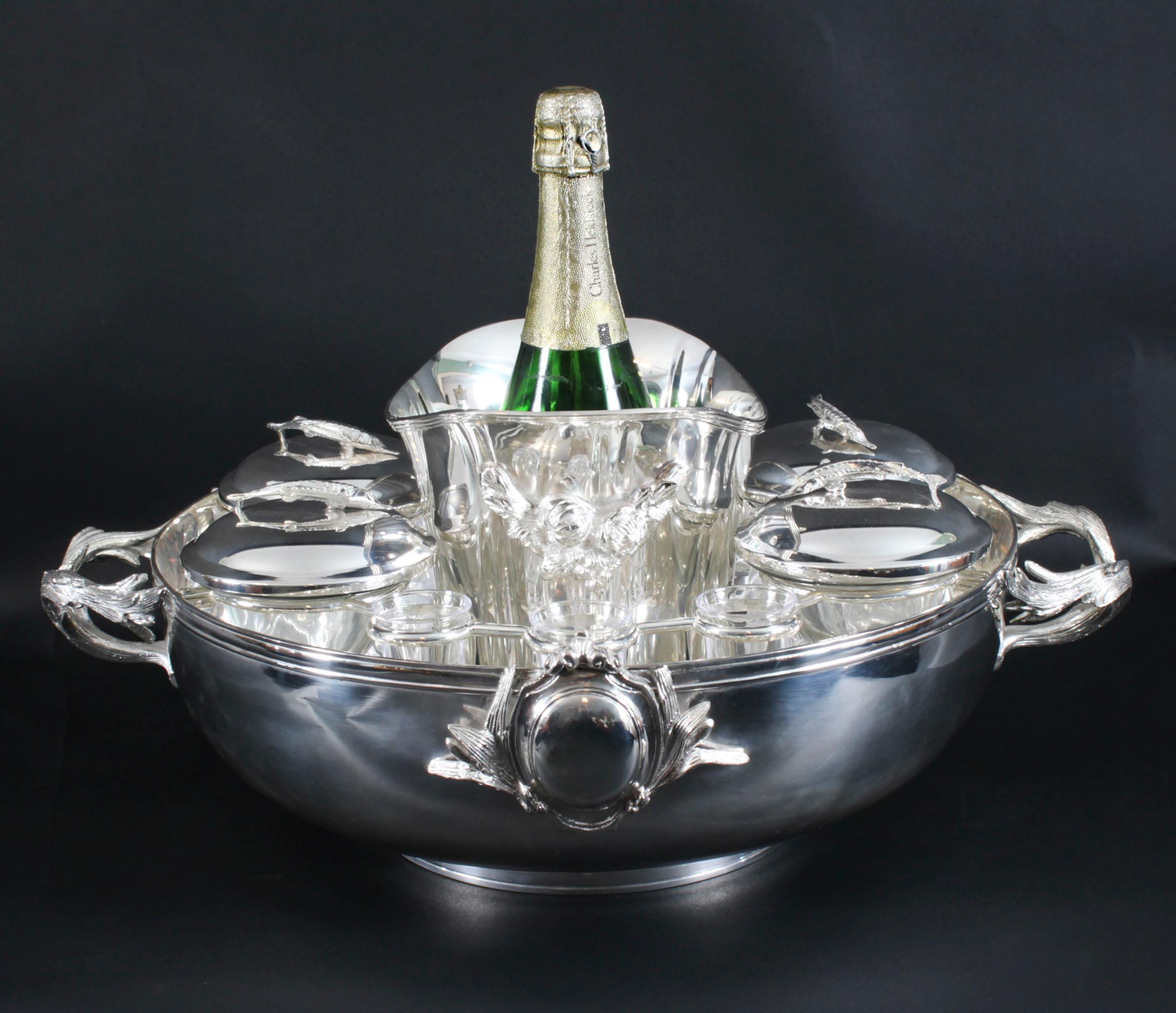 Precioso set de caviar y champán/vodka vintage bañado en plata. Consta de cuatro platos de caviar de cristal y tapas bañadas en plata, un enfriador de champán/vino en el centro y seis vasos de chupito de vodka alrededor, y data de la segunda mitad