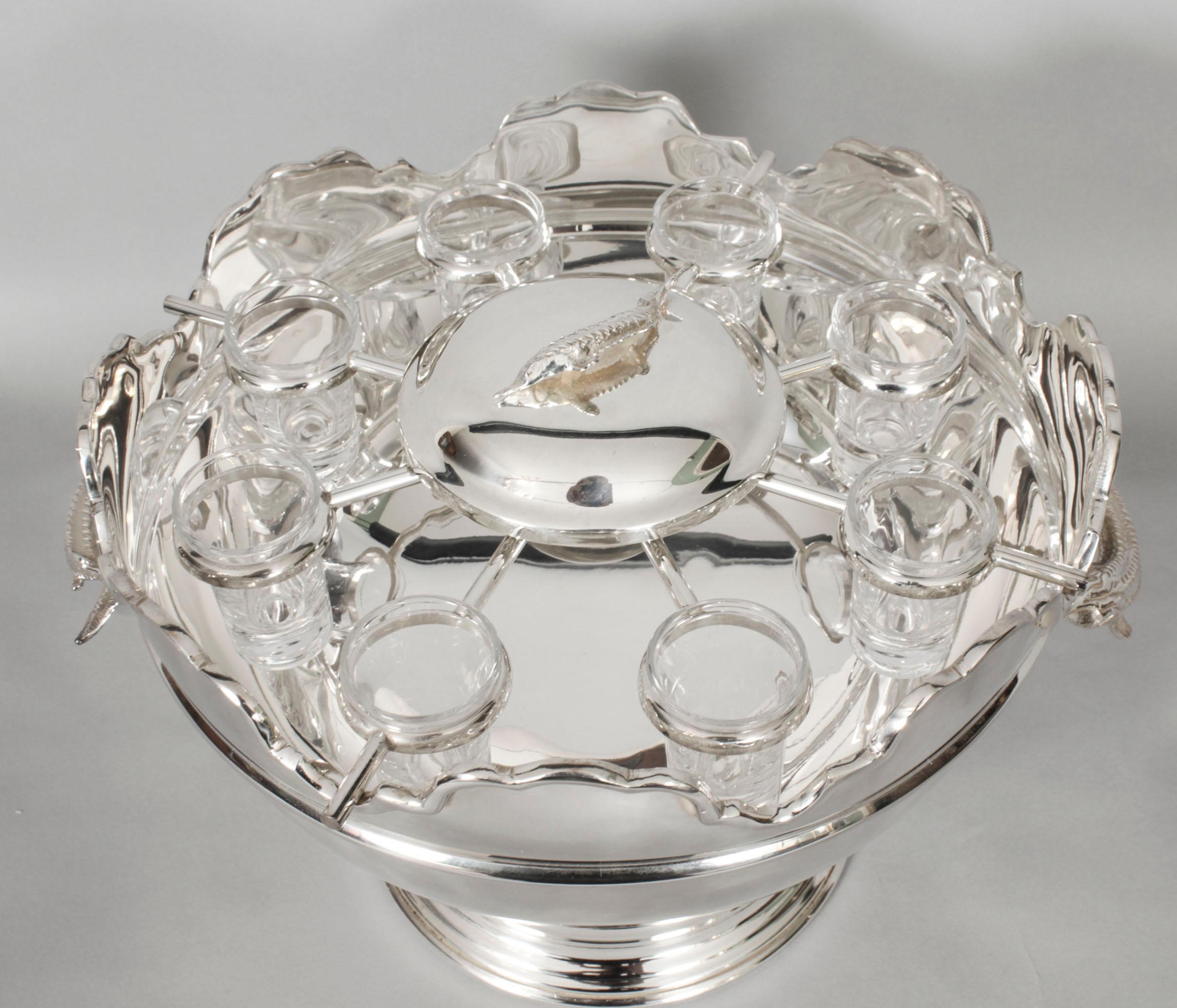 This is a gorgeous  Vintage silver plated Monteith caviar set with a caviar dish and cover in the centre and eight vodka shot glasses around it, dating from the second half of the 20th Century.

It has decorative silver plated sturgeon handles with