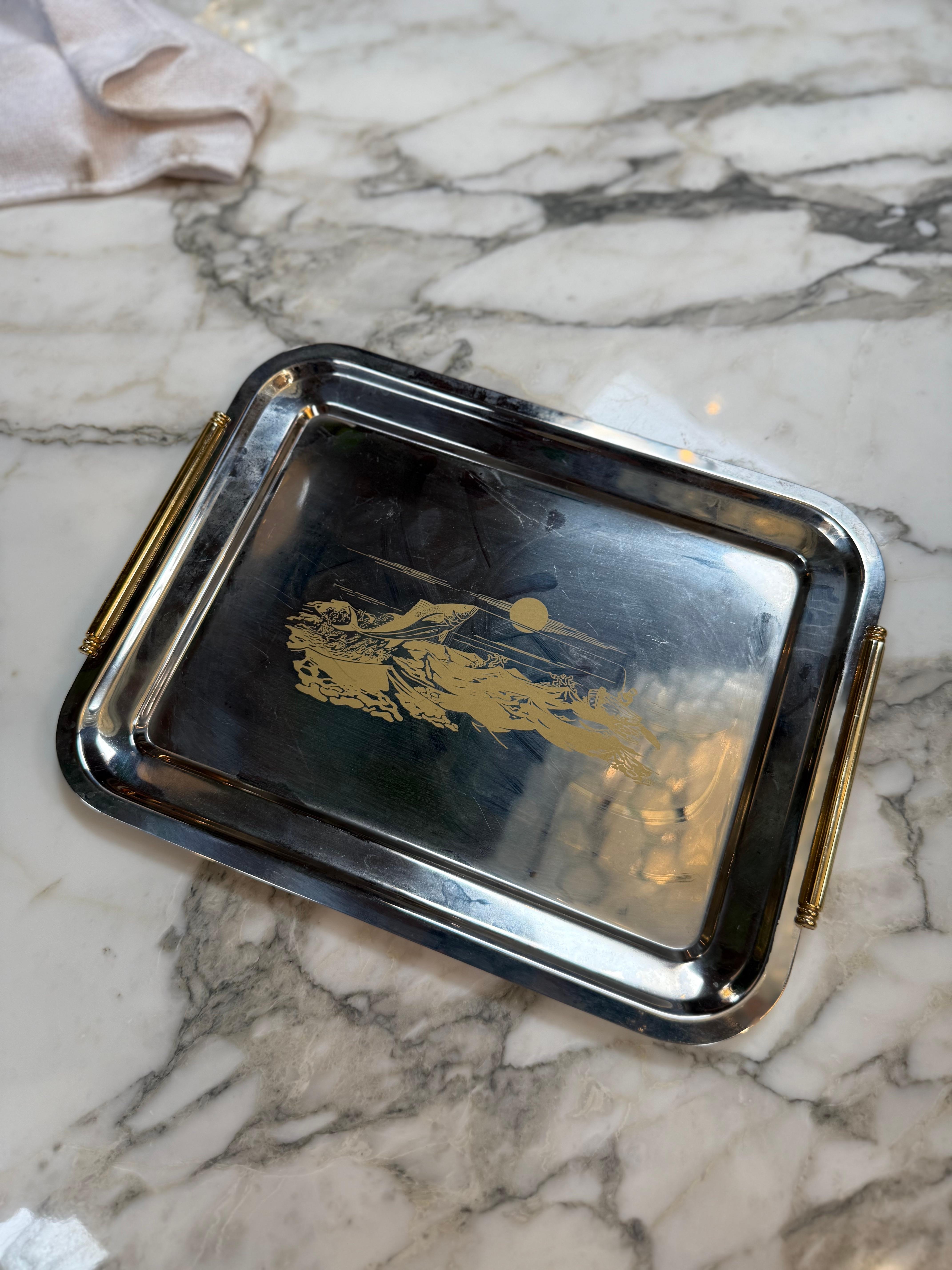 This elegant vintage metal serving tray features a refined scenic motif beautifully engraved in gold tone at its center. The design depicts a serene landscape, with a sun or moon rising over the horizon, creating a timeless and tranquil composition