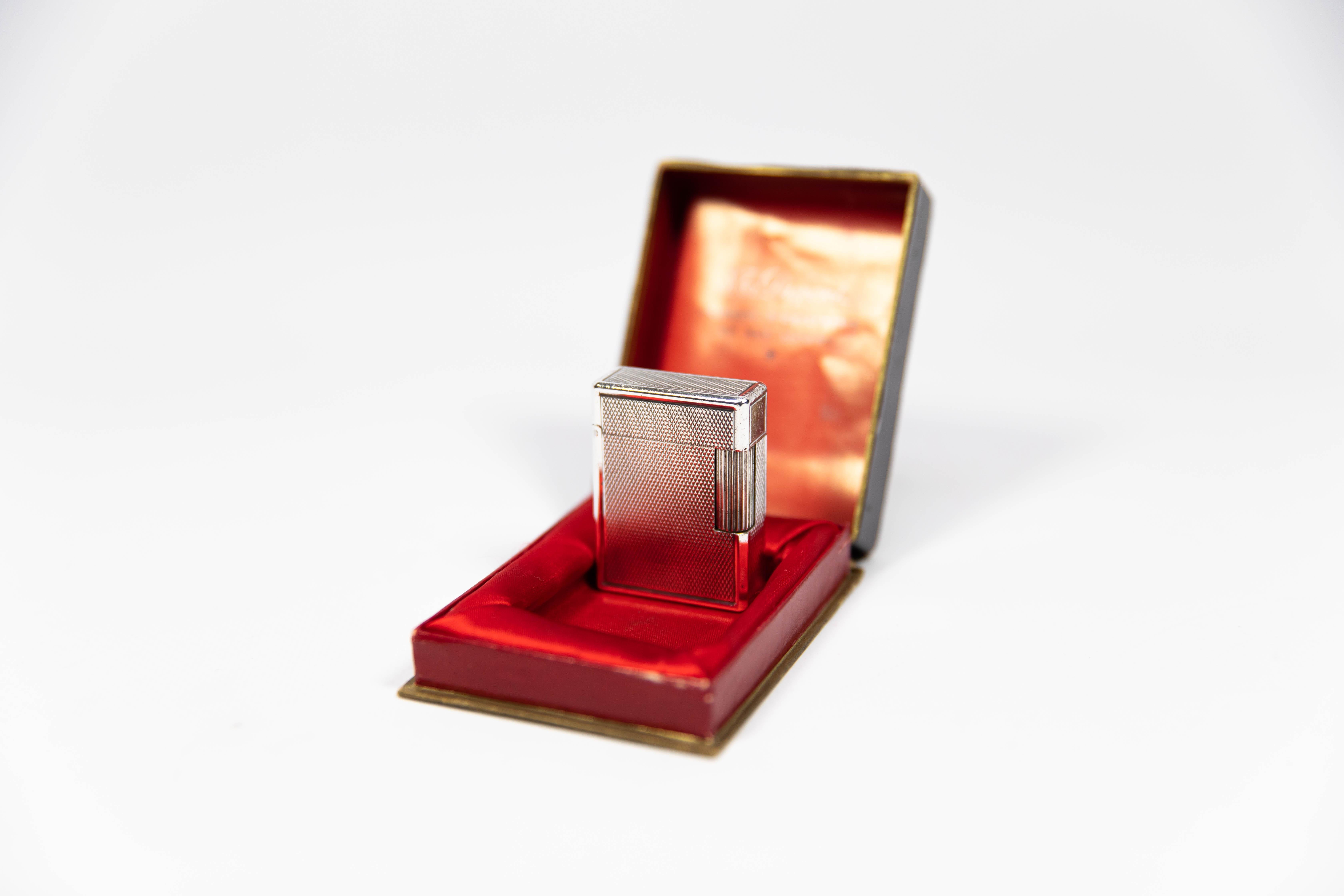 Vintage Silver Plated Small Linge 1 BS ST Dupont Lighter 1970s In Box

The iconic S.T. Dupont name is known for quality, well-made cigarette lighters and other luxury implements. The company’s origin can be traced to Simon Tissot-Dupont opening his