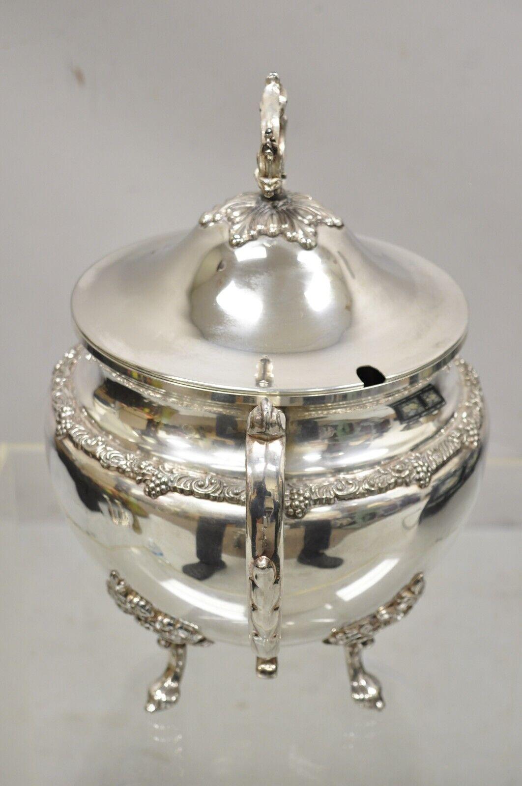 Vintage silver plated soup tureen serving pot with lid and fancy twin handles. Item features a lid with cutout for ladle, ornate handle, ornate twin handles marked 