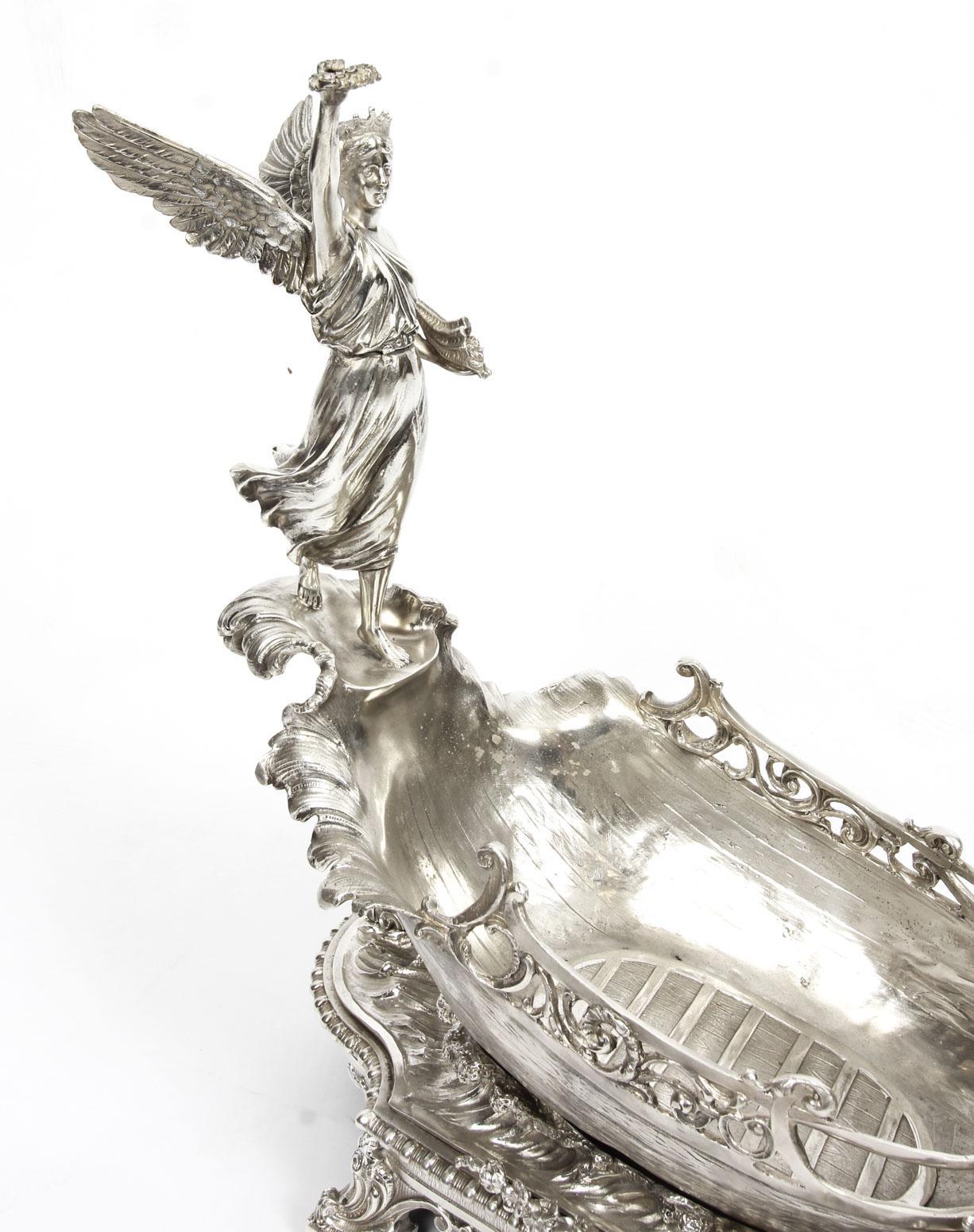 A stunning vintage silver plated centrepiece in the shape of a boat riding the waves preceded by a swan with the winged Victory of Samothrace, dating from the second half of the 20th century.

This stunning piece is ideal for displaying fruit or
