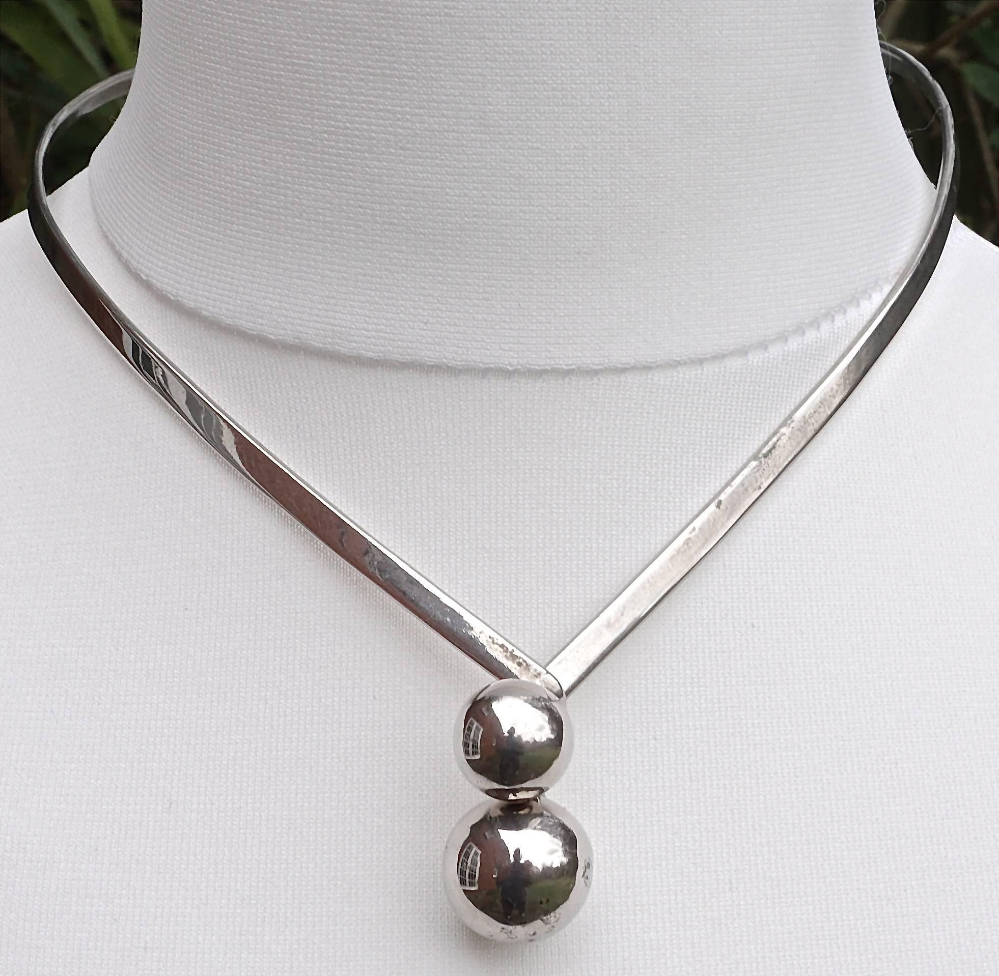 Stylish silver tone torque necklace, featuring two simple interlocking balls that fasten at the front. Length approximately 43cm / 17 inches, and width 4mm / .16 inches. The silver balls are length 2.8cm / 1.1 inch, and the largest ball is diameter