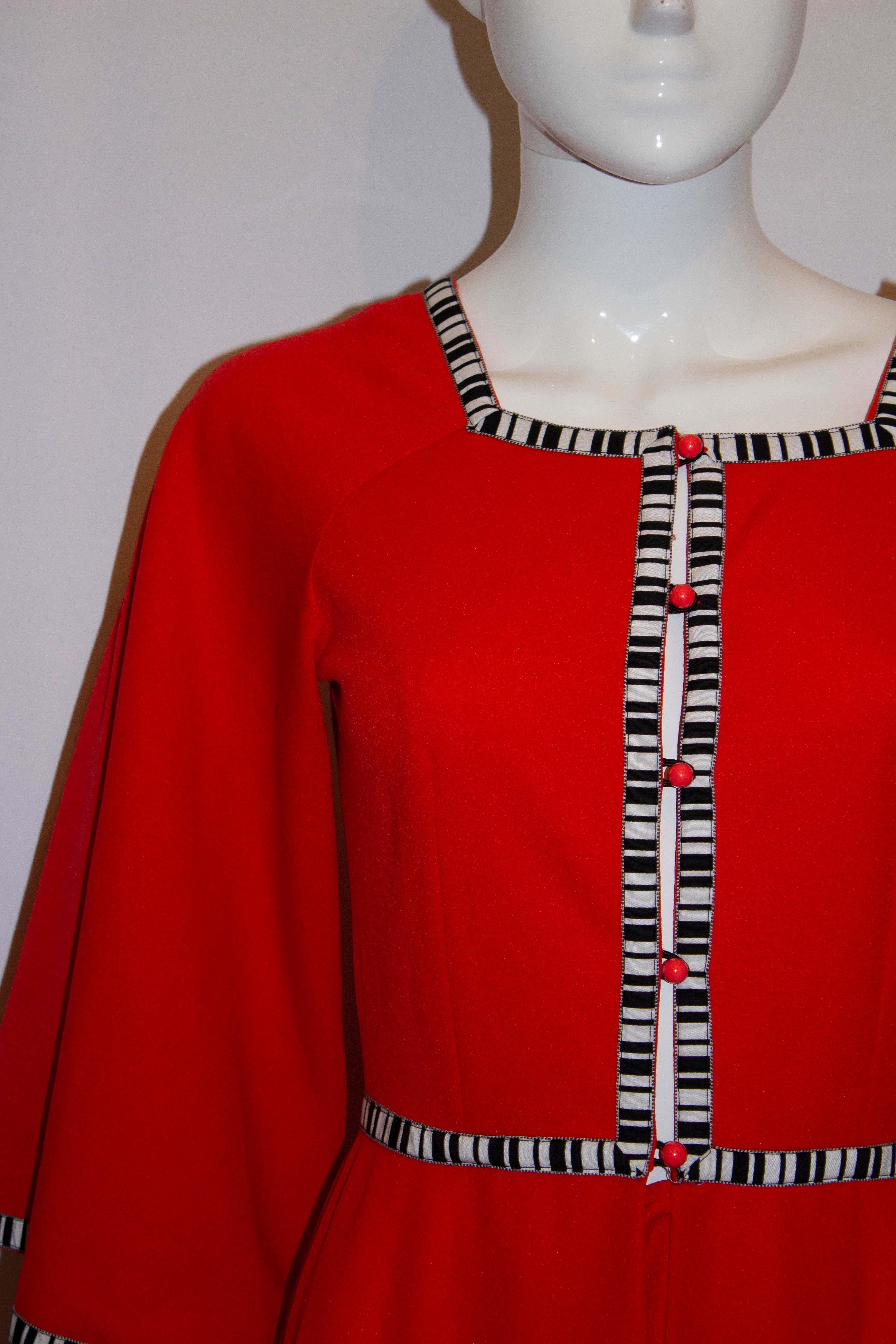 A headturning vintage dress by Simon Ellis . The dress is in a red jersey fabric , with black and white trim and a button opening at the front. Measurements: but 34'',length 58''