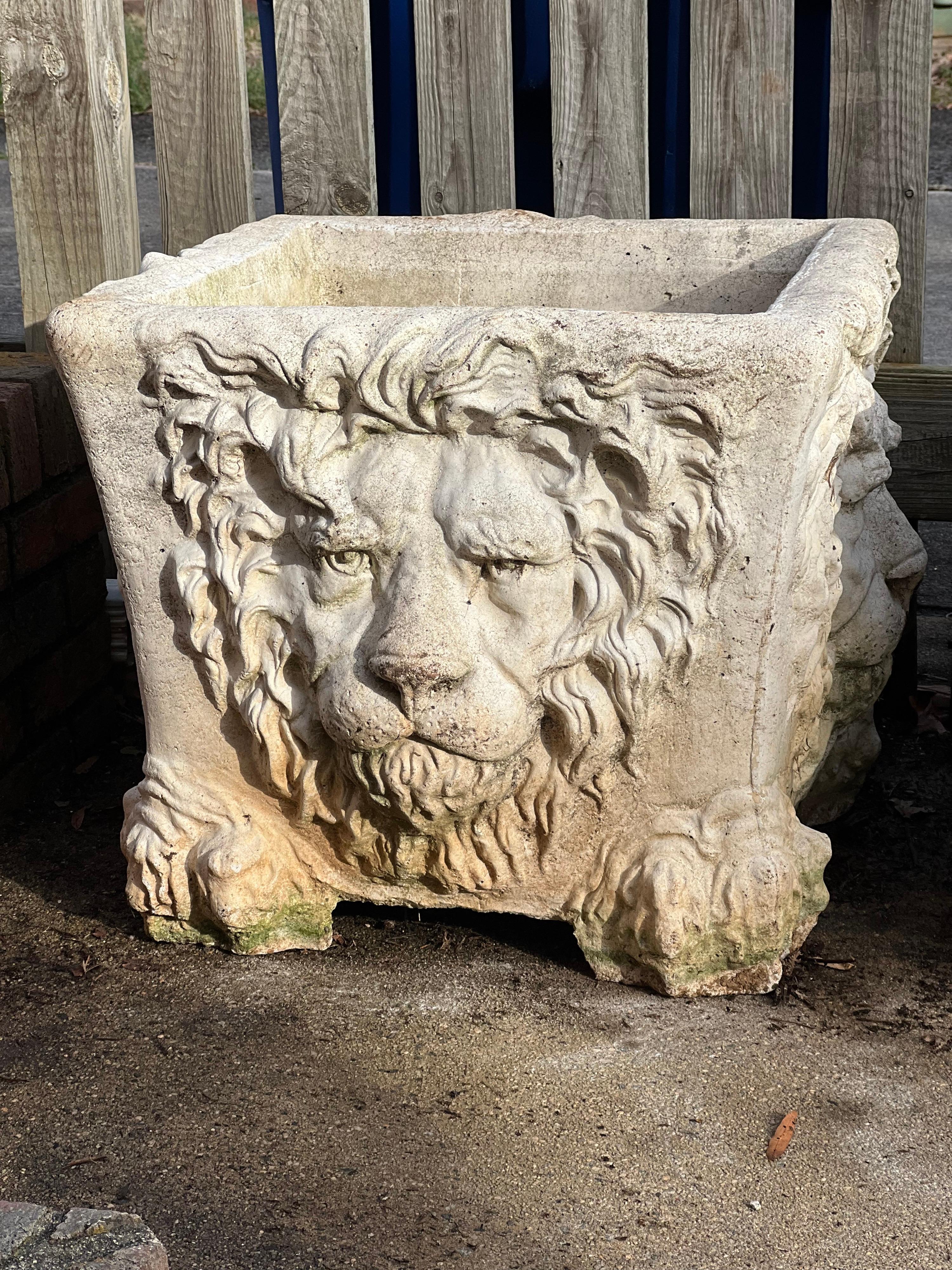 Magnifique jardinière en pierre moulée. Les quatre côtés sont ornés d'un visage de lion. 

Patine naturelle légère.