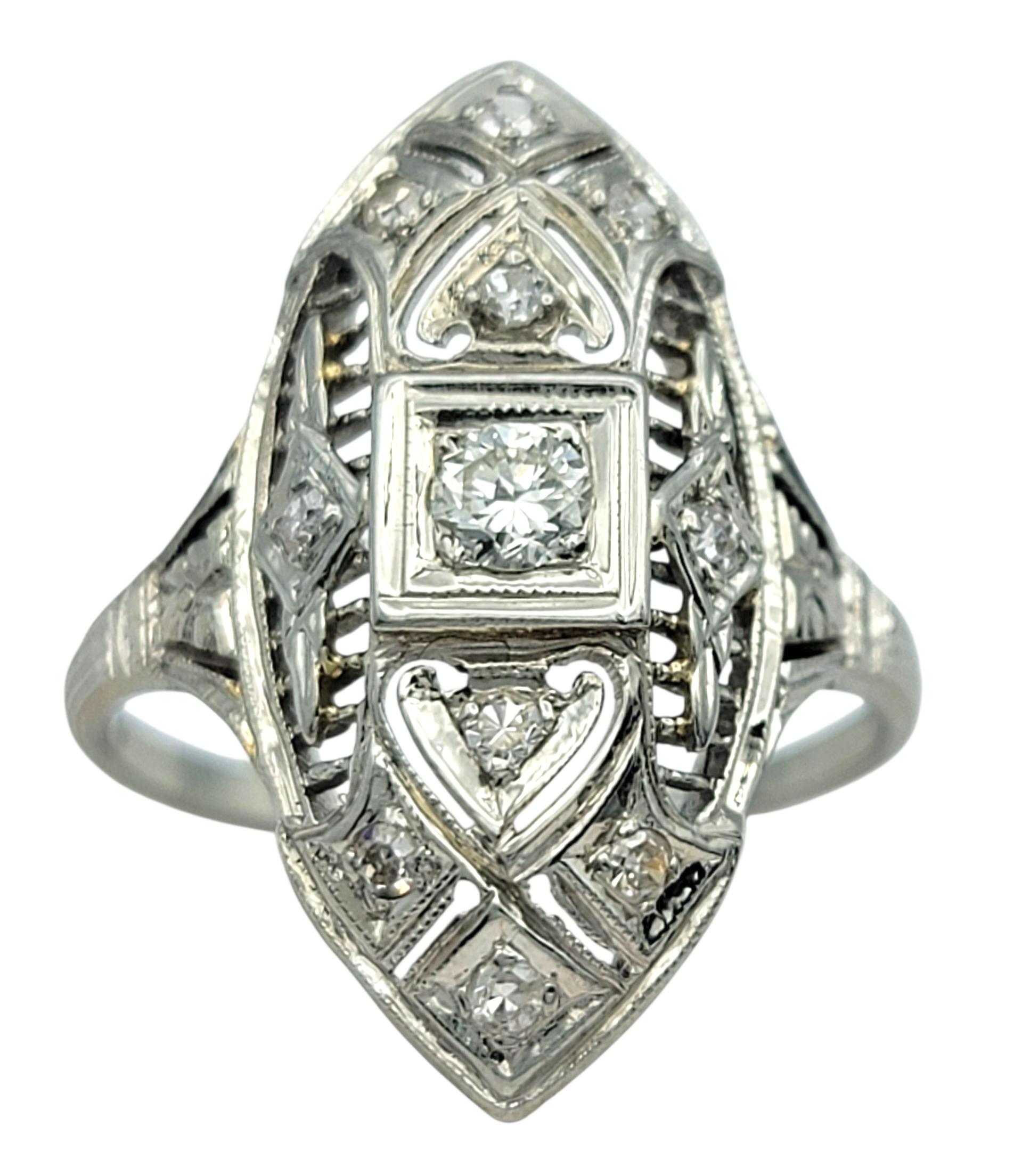 Ringgröße: 7

Dieser filigrane Ring im Vintage-Stil besticht durch sein kunstvolles, durchbrochenes Design und sein geometrisches Rautenmuster. In der Mitte befindet sich ein runder Diamant, der von einer Reihe von Formen mit Maserung umrahmt wird,