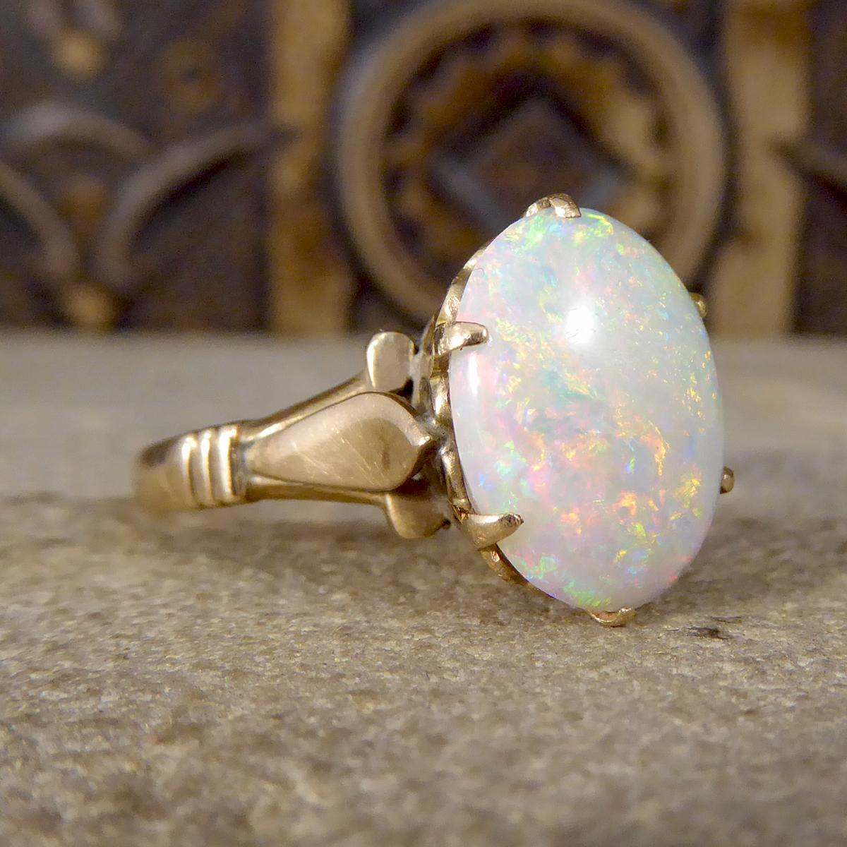This lovely vintage ring has been crafted from 9ct Yellow Gold with a single large Opal. The cabochon Opal shows a variety of colours glimmering in the light, it accentuates warm oranges and reds in most light with clear colour shining through. The