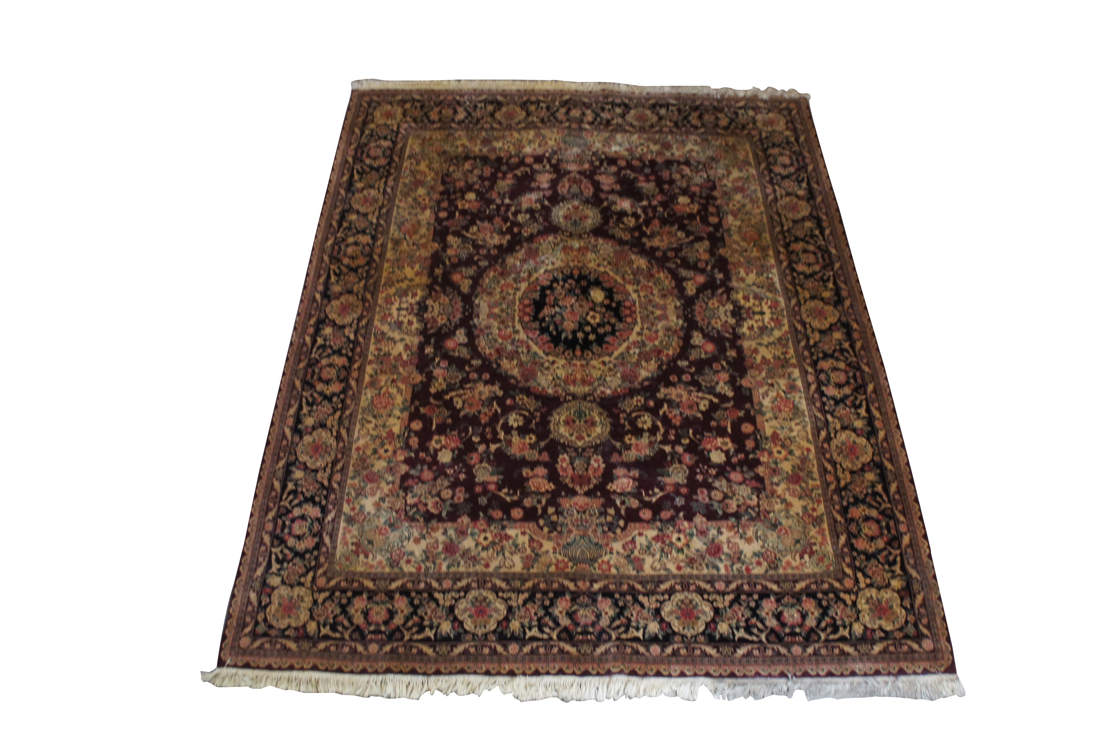 A medium sized Persian Sino Yazd wool area rug. Yazd rugs are made in Yazd Iran and known for their rich Burgundy floral patterns. This rug features a hand knotted pile with round central medallios surrounded by geometric floral sprays. A beautiful