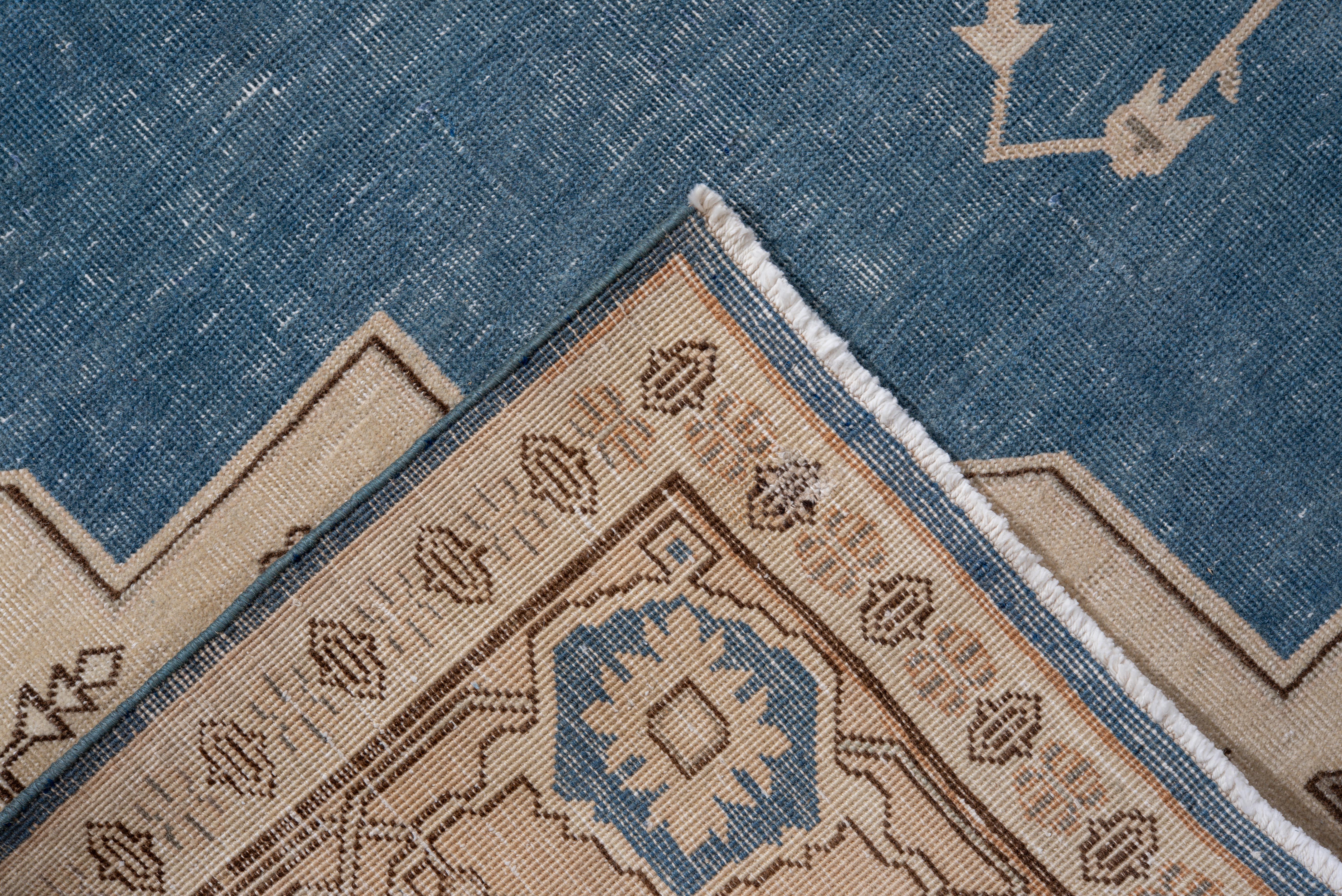 Esta alfombra vintage de Sivas presenta un luminoso campo azul cielo bellamente contrastado por un medallón central crema adornado con estilizadas palmetas, viñedos y angulosos motivos botánicos en cálidos tonos topo y contornos de cacao. Las