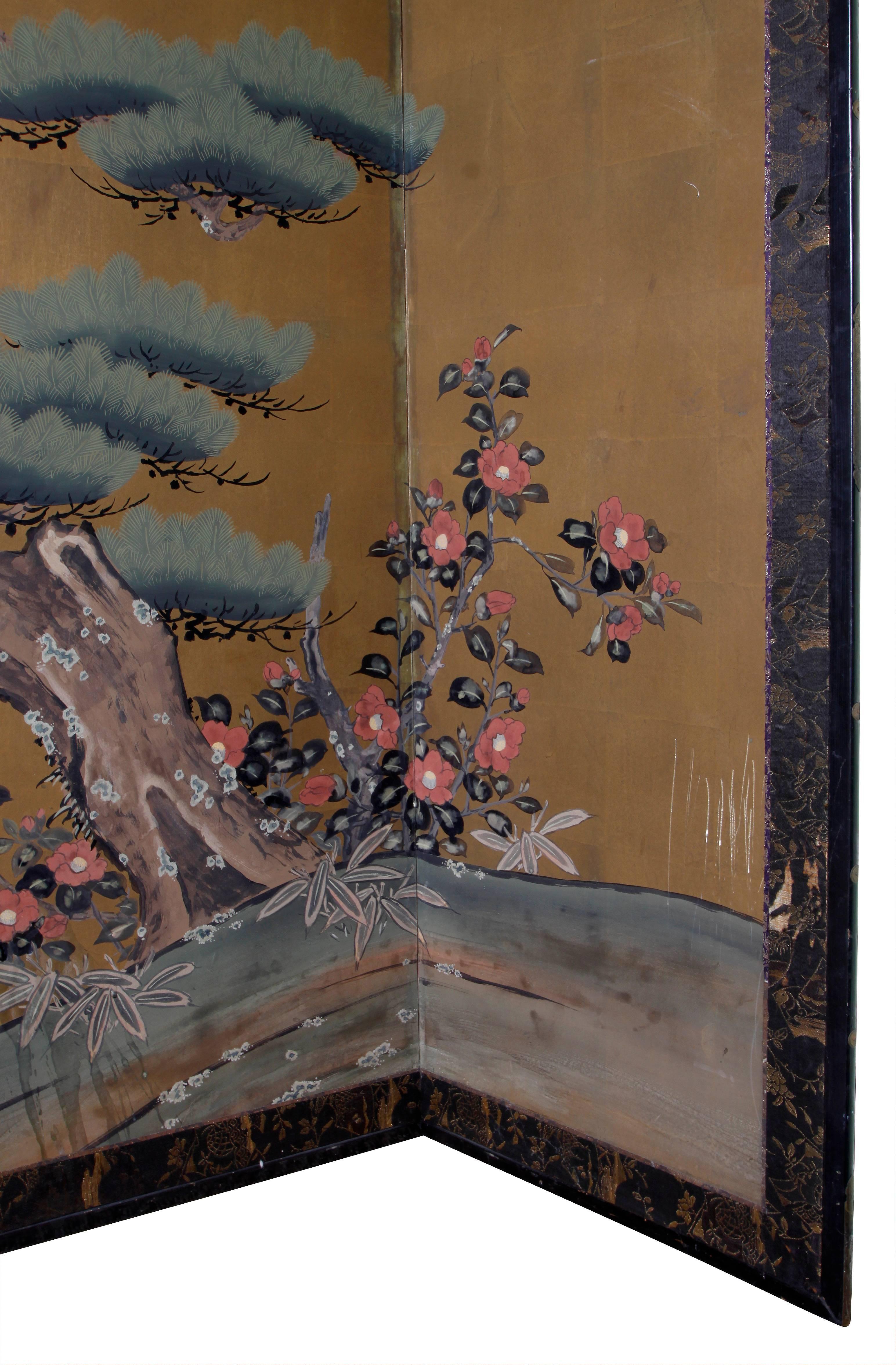 Vintage six-panel Asian screen with gold leaf decoration. Scenic rendering of a sculpted tree, flowers and a river.