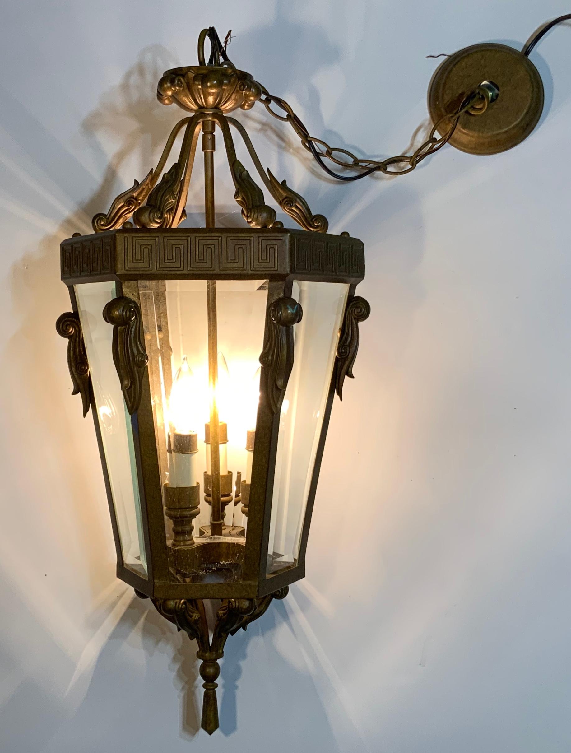 Vintage hanging lantern made of metal with three 60/watt light. Beveled glass on six sides, beautiful Greek key top decoration, and composition resin decoration on top and bottom.
Original canopy and chain included.