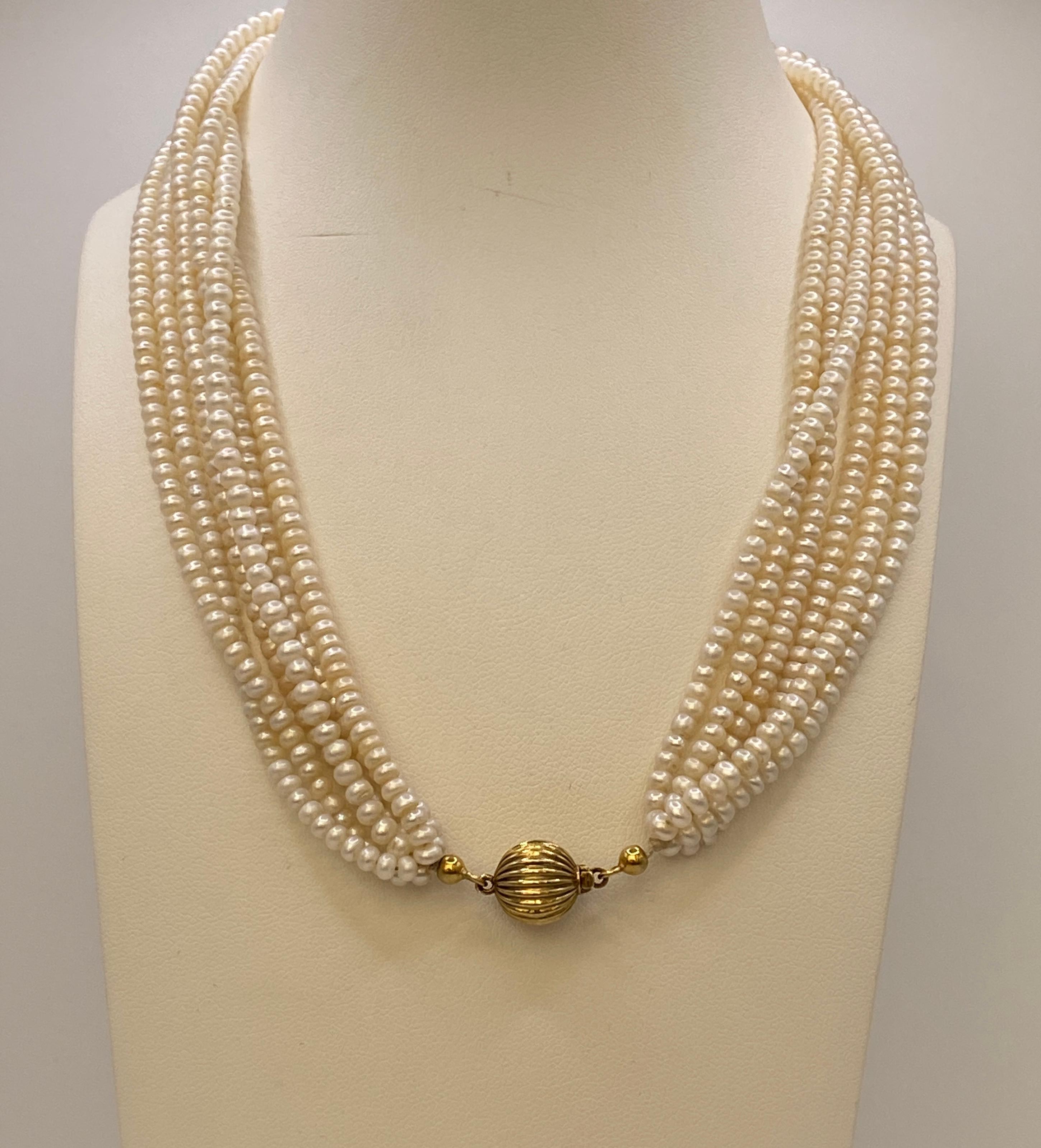 Vintage Six-Strand Fresh Water Button Pearl Choker Necklace with gold clasp.
This stunning vintage choker features six strands of luminous freshwater button pearls, beautifully arranged to create a rich, layered look. The pearls showcase soft,