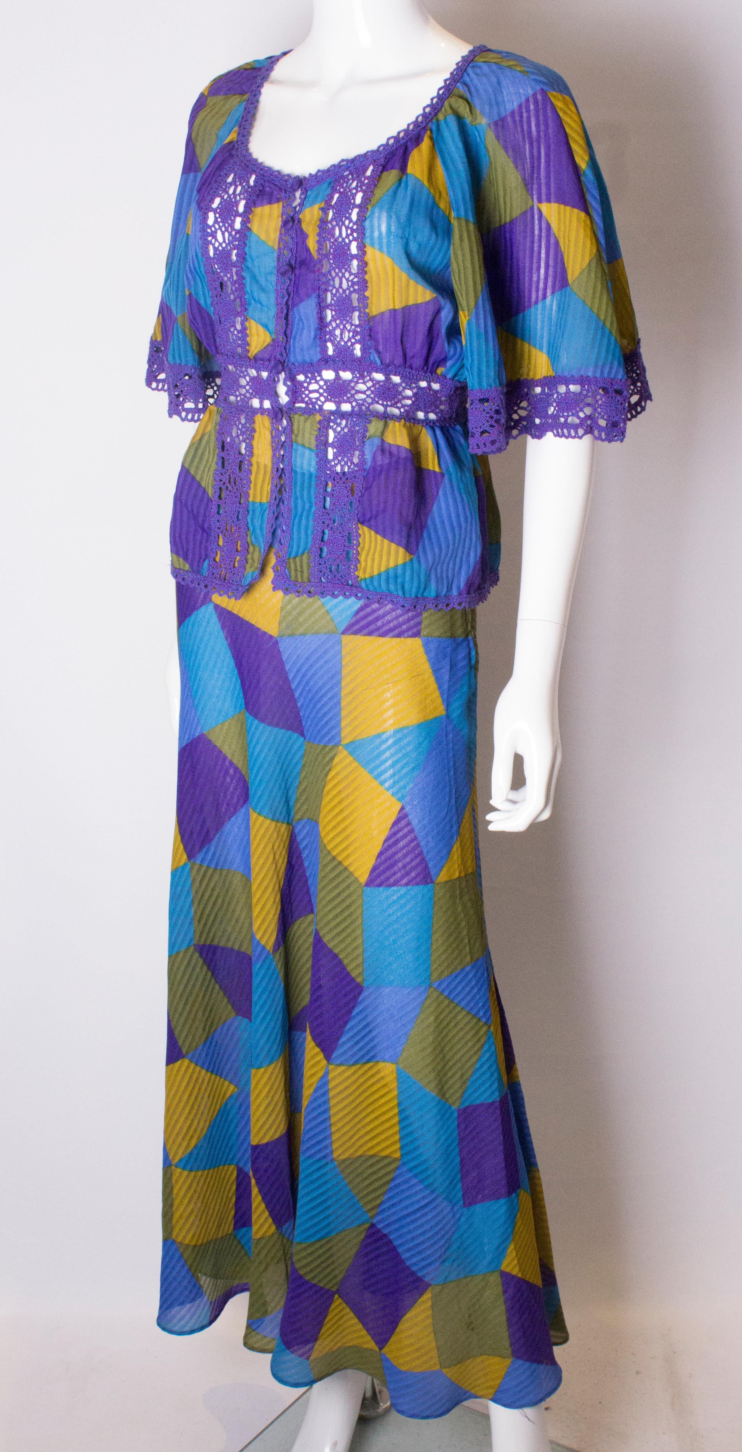 A fun top and skirt by Frank Usher. The outfit is in purple, ,green ,mustard , and blue.
The skirt has a side zip opening and the top has a 4 button front opening. 
Measurements: Skirt 26'', length 41'', jacket bust 36'', waist 27'', length 23''