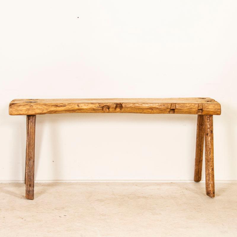 It is the thick natural wood top that one finds intriguing in this rustic table. It originally served as a work table, resulting in the rugged worn patina of the wood top due to the deep gouges, scrapes and old cracks. The small cut out sections on