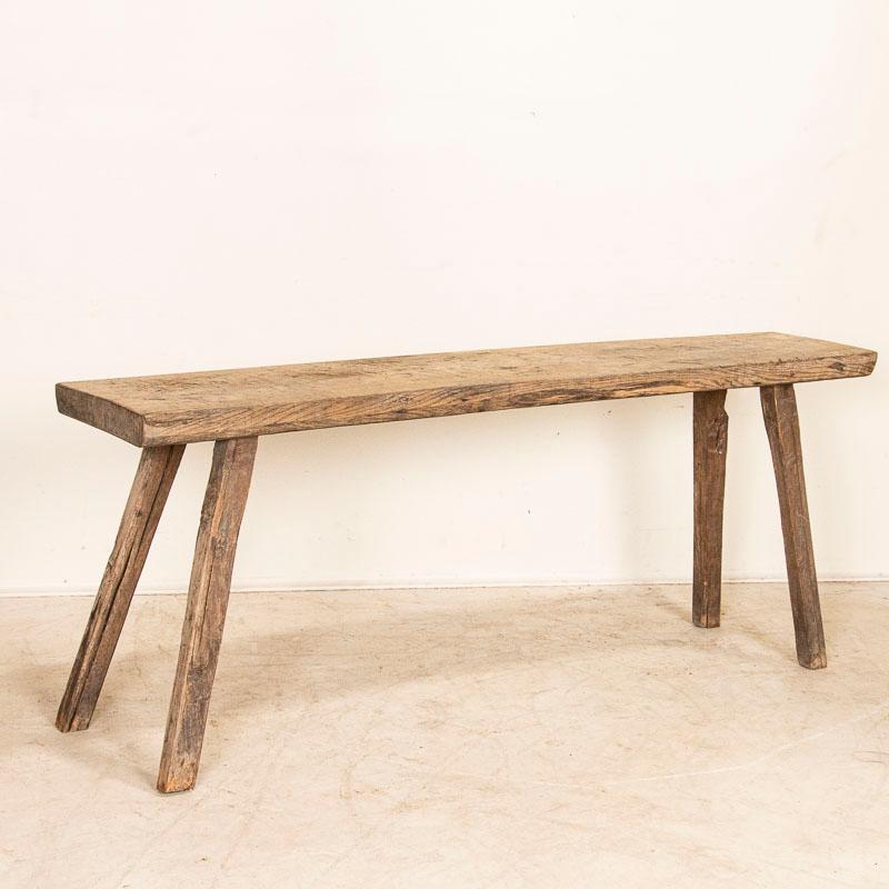 The slab wood top of this console table has an organic feel that draws one to it while the deep gouges, marks and distress combine to make this rustic table so unique. Originally, this was likely a work table for a butcher or carpenter and now