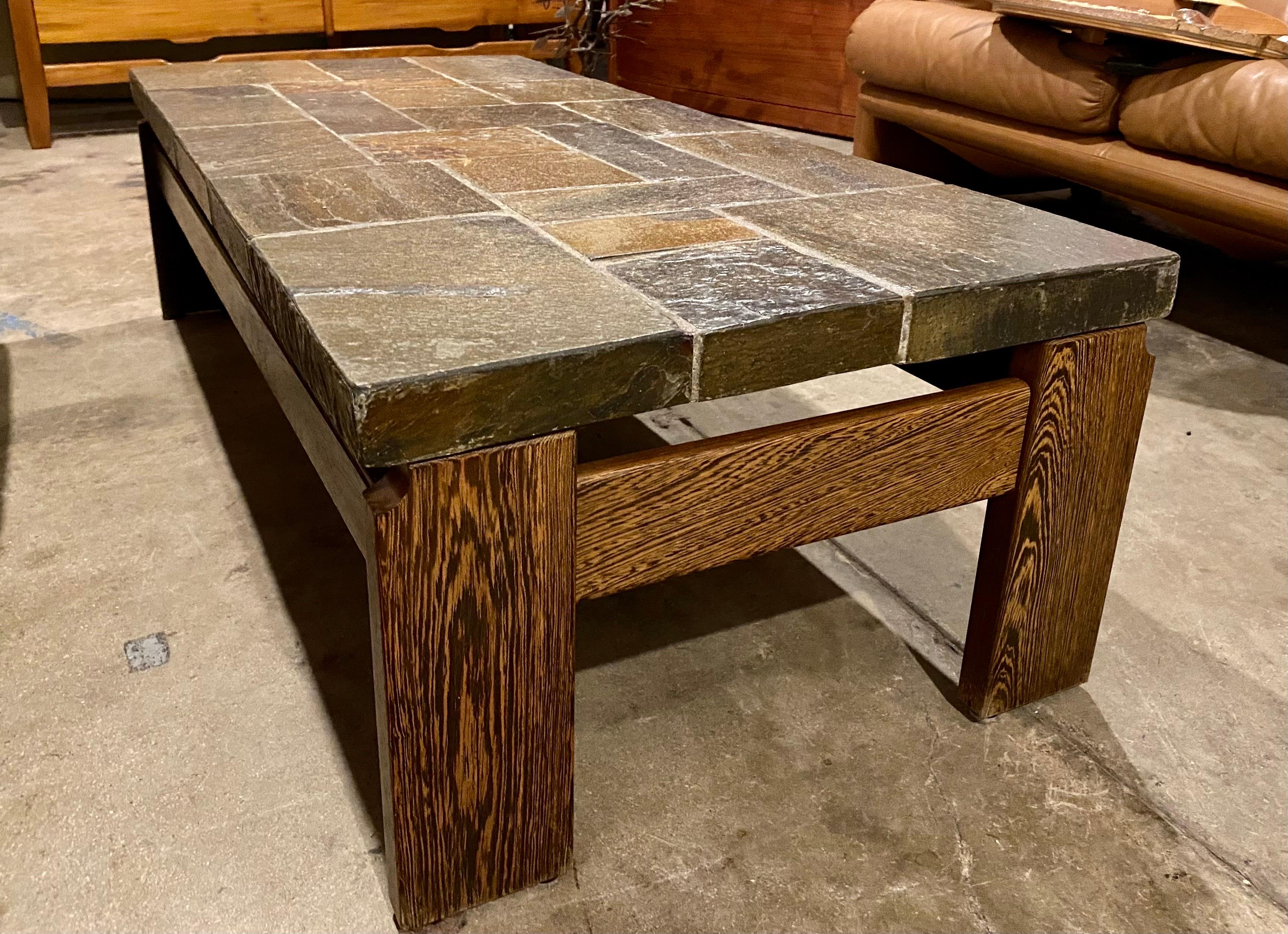 Vintage slate top coffee table with a wood base made of wenge, Belgium, circa 1970s. This vintage brutalist coffee table is very heavy, sturdy and in good overall condition. 
Dimensions: 51.25