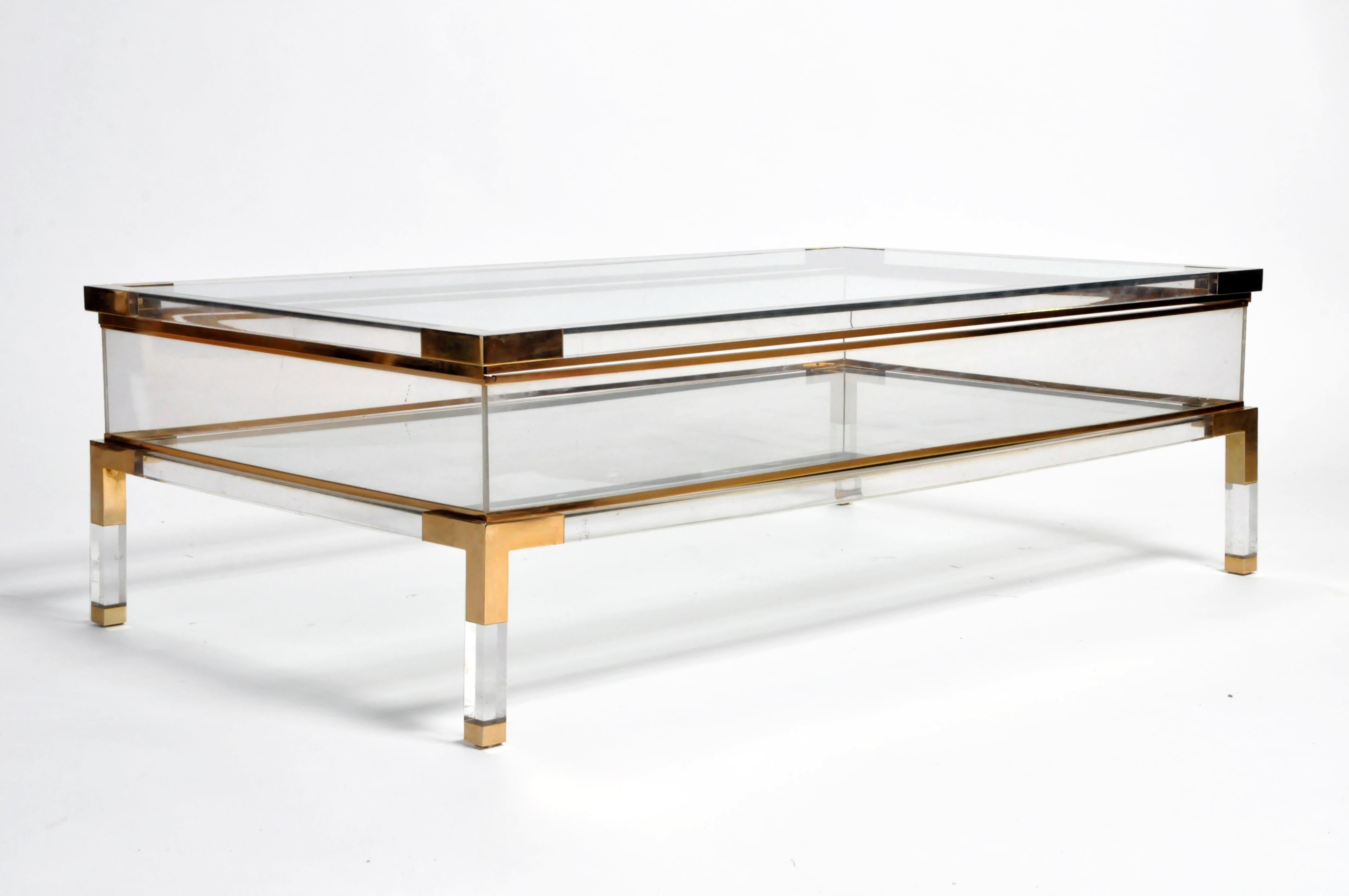 This sleek vitrine table has a glass top that slides opens to reveal a storage space below. Walled with Lucite, the clear glass bottom shelf allows the chrome frame to show through; the effect is airy and angular. This versatile display case is a