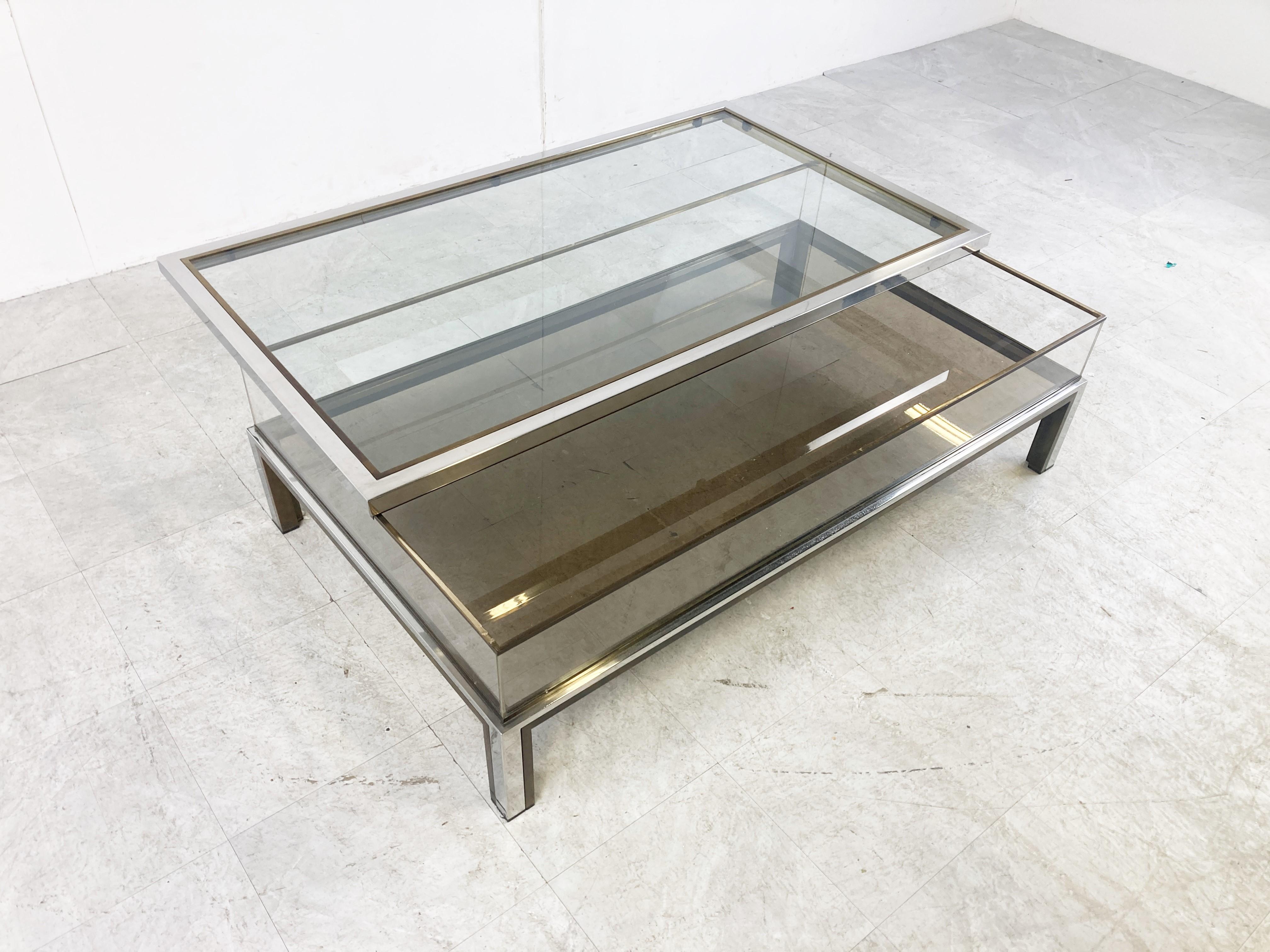 Vintage display coffee table with a sliding glass top.

This luxurious coffee table is made from brass, glass top and bottom and plexiglass sides.

It is ideal to display curio and store magazines,.

Good condition

1970s -