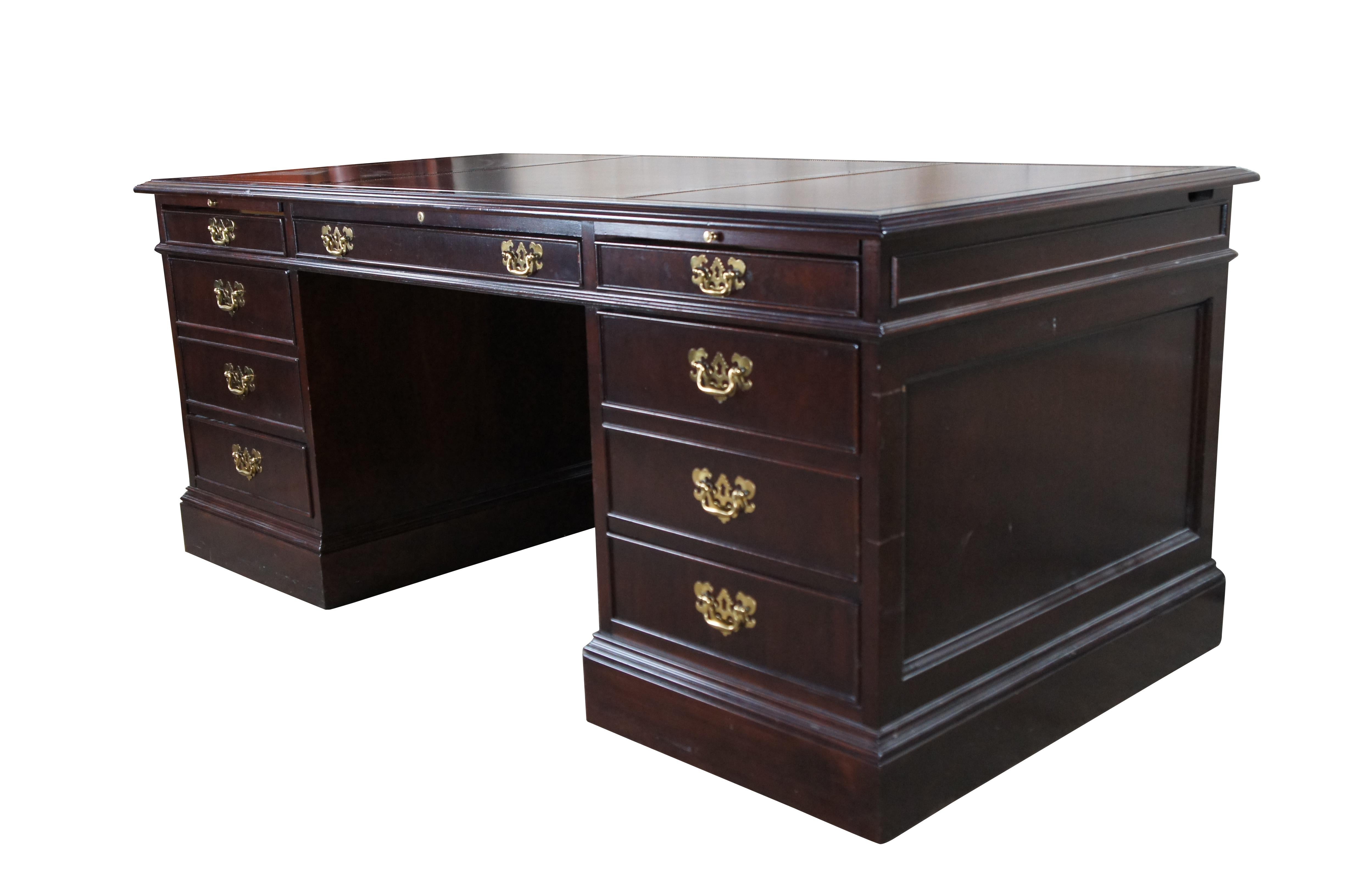 1980s Sligh Furniture Company Executive Desk. Made in Holland, Michigan. Features a rectangular form made from mahogany with a burgundy tooled leather inset top. The desk features seven dovetailed drawers made from oak with English Chippendale-style