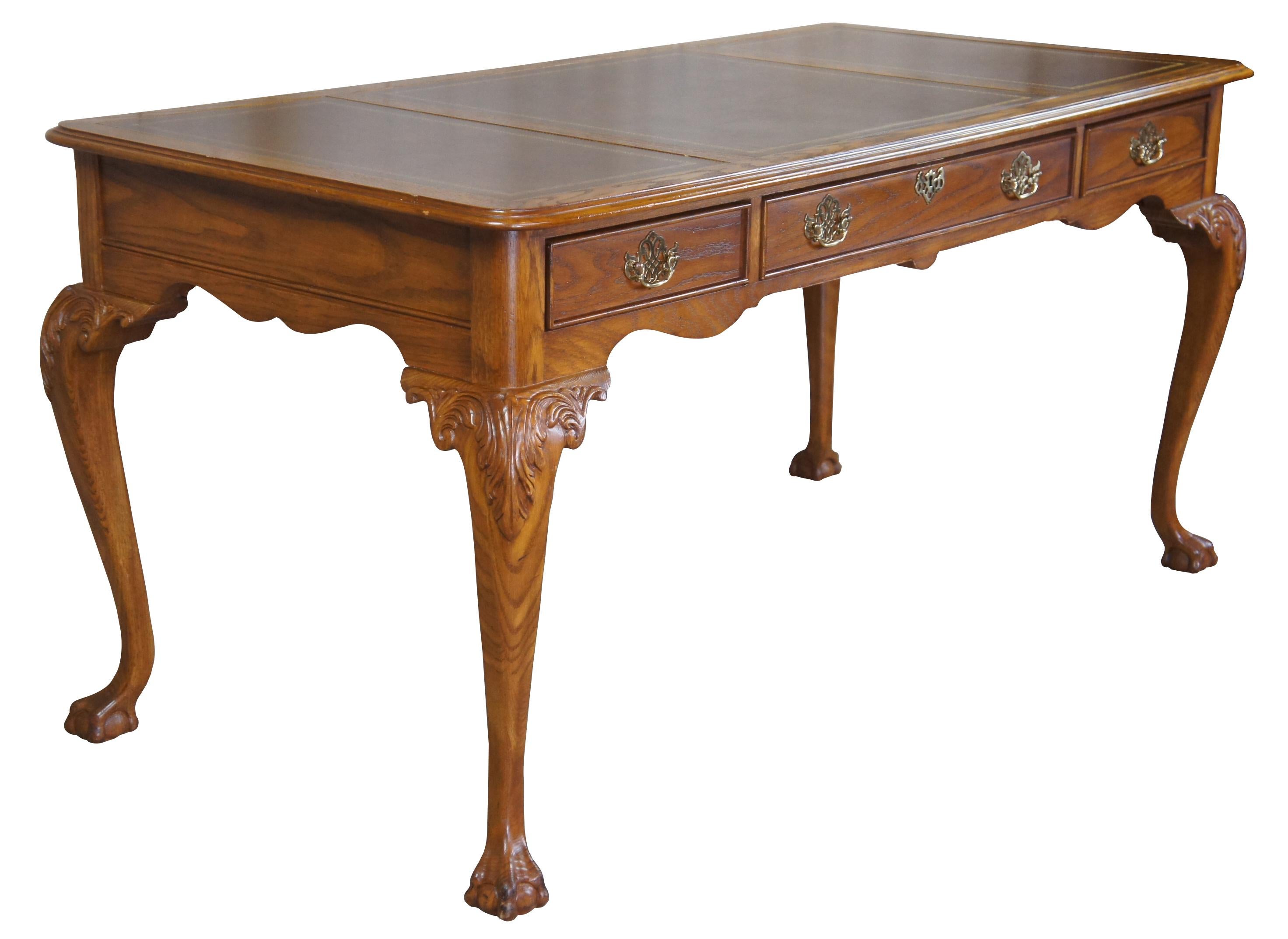 Vintage Sligh Furniture Queen Anne writing desk. Made of oak featuring tooled leather top, three drawers and scrolled legs leading to ball and claw feet. Measure: 60