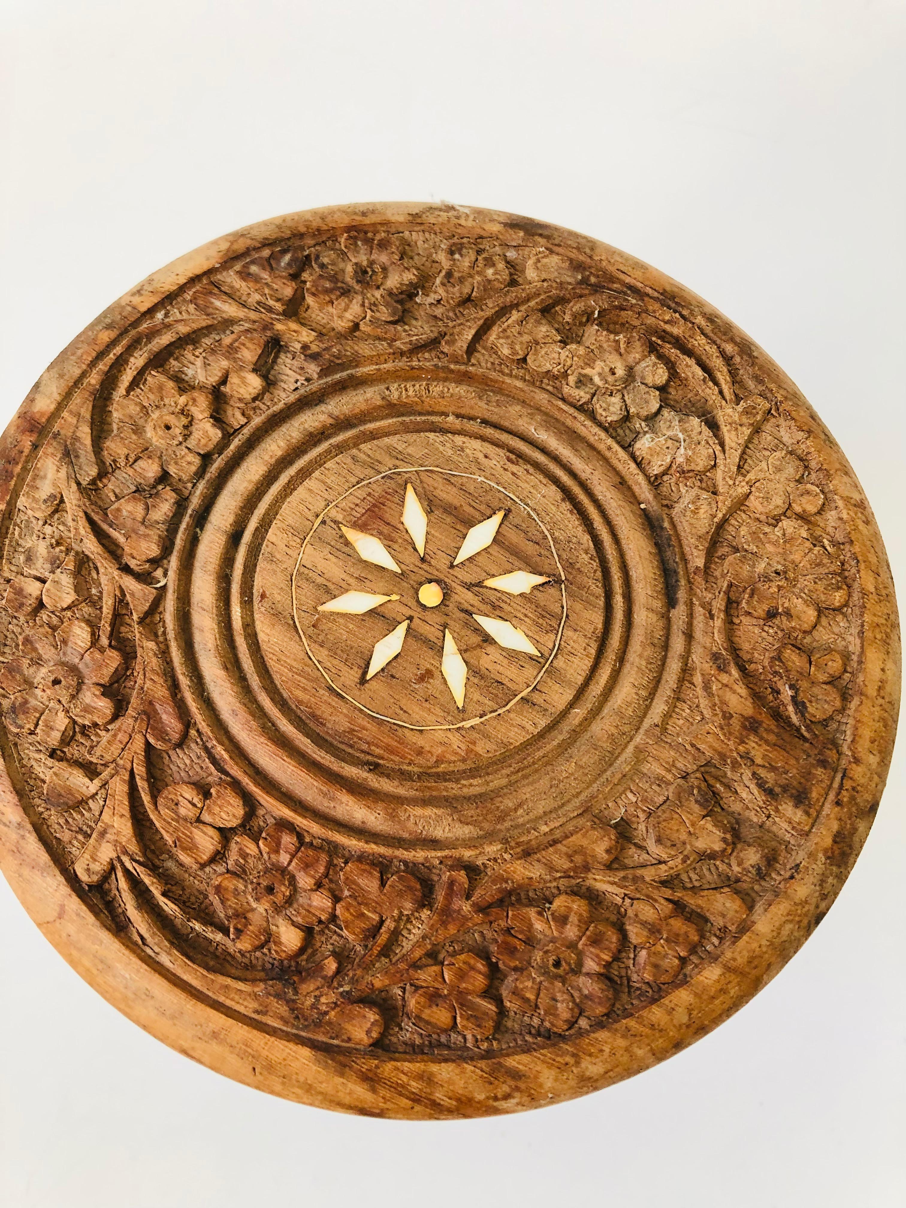 A lovely vintage circular wood plant stand on a 3 legged base. Lovely hand carved floral detailing throughout with a white stone floral inlay in the center. disassembles for storage and shipping.
 