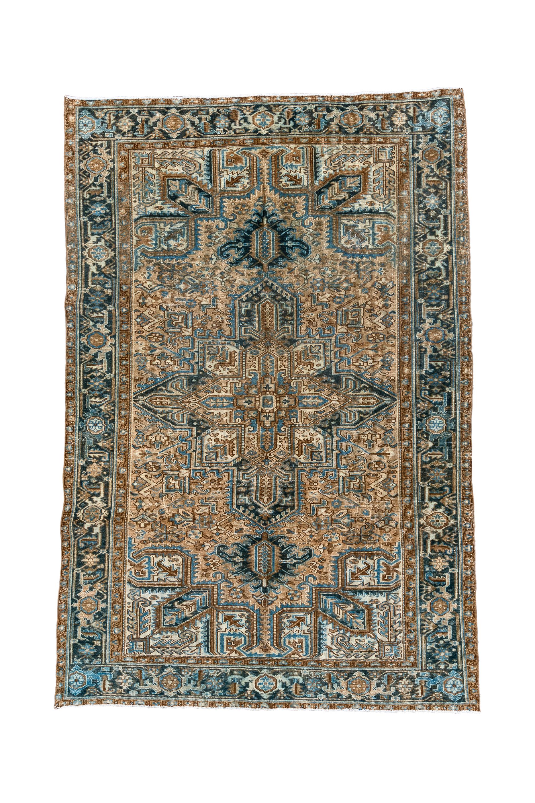 This NW Persian village piece shows a light coral field, a navy and cream octogramme medallion and ecru corners defined by barbed stiff leaves. Torn palmette medallion pendants in navy. Near black strip style main border with reversing turtles.