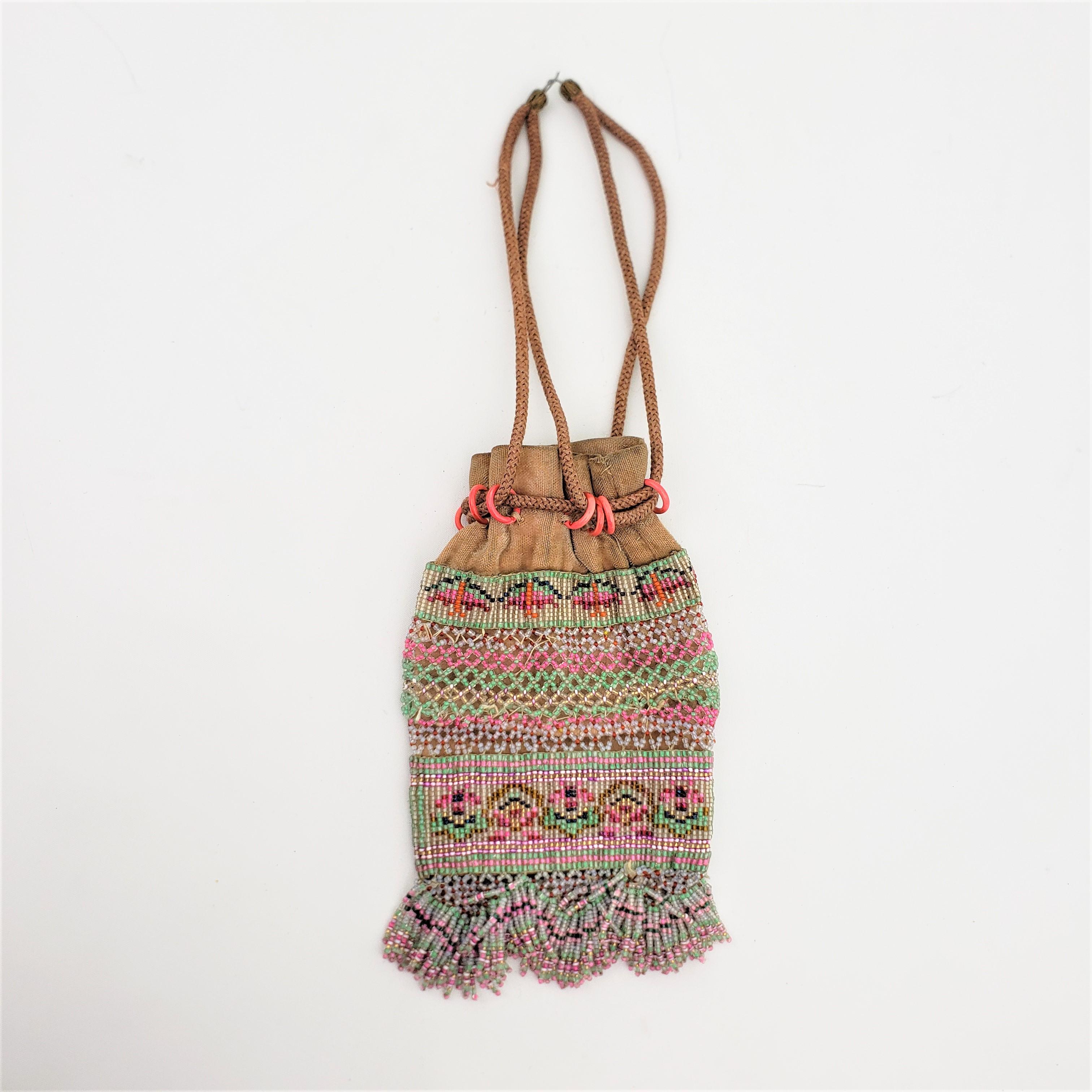 This small hand-crafted beaded leather pouch or tobacco bag is unsigned, but presumed to have been made in the United States in approximately 1970 in an Indigenous American folk art style. The bag itself is composed of a heavy leather with a series