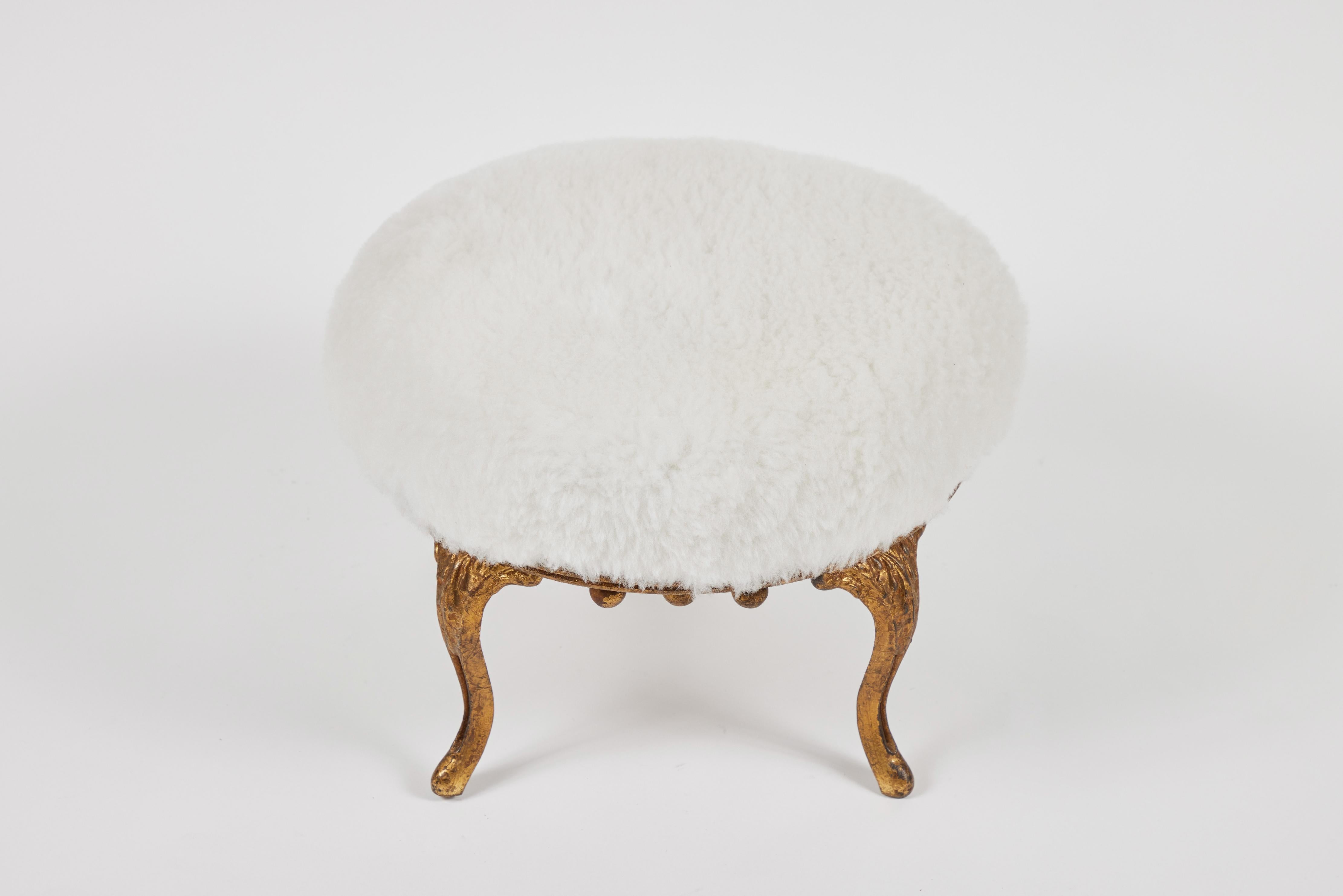Vintage small wood footstool with gold iron legs and decorative accents with a newly upholstered white shearling cushion.