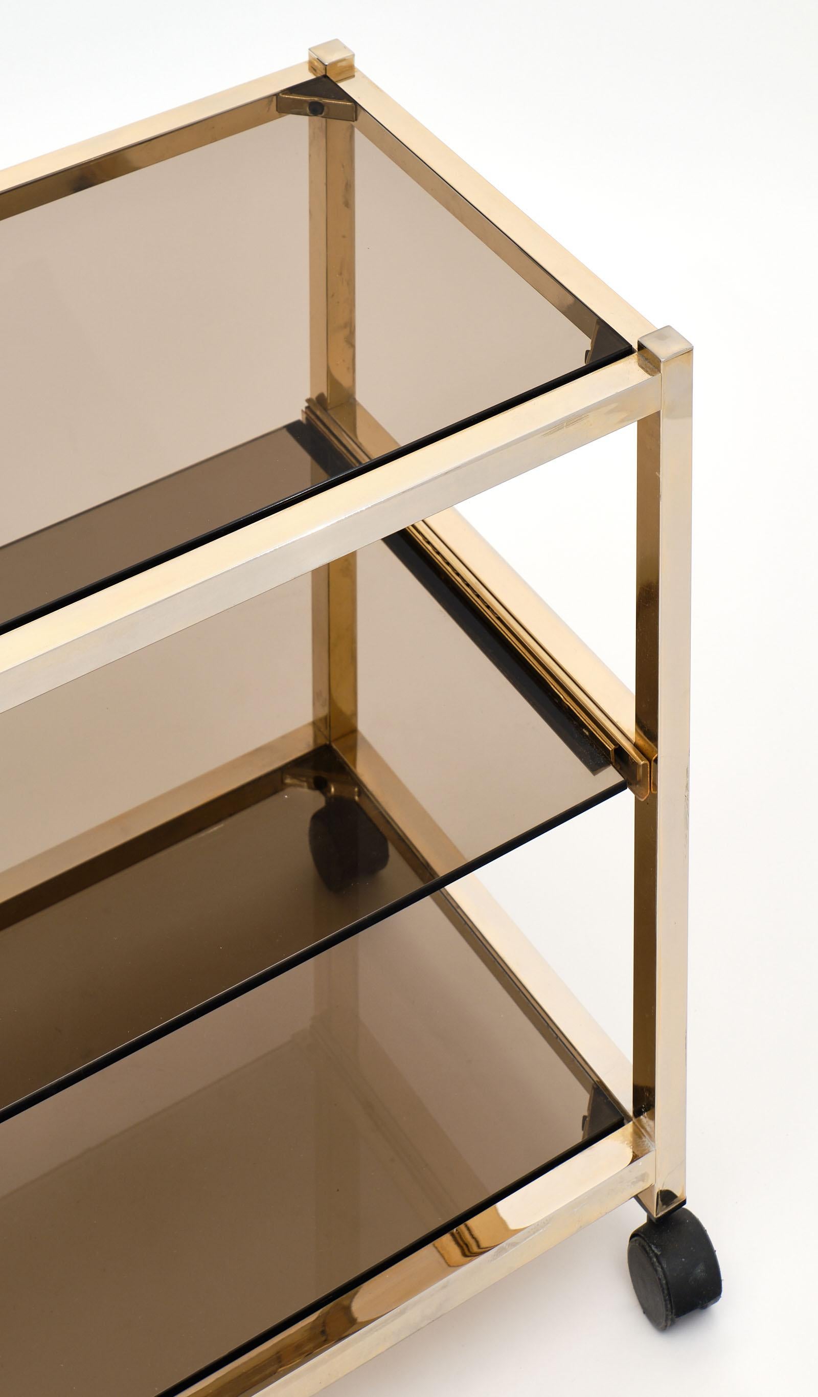 Vintage smoked glass side table on original casters and featuring a sliding middle glass shelf. We love this brass piece with both function and excellent modernist aesthetics.