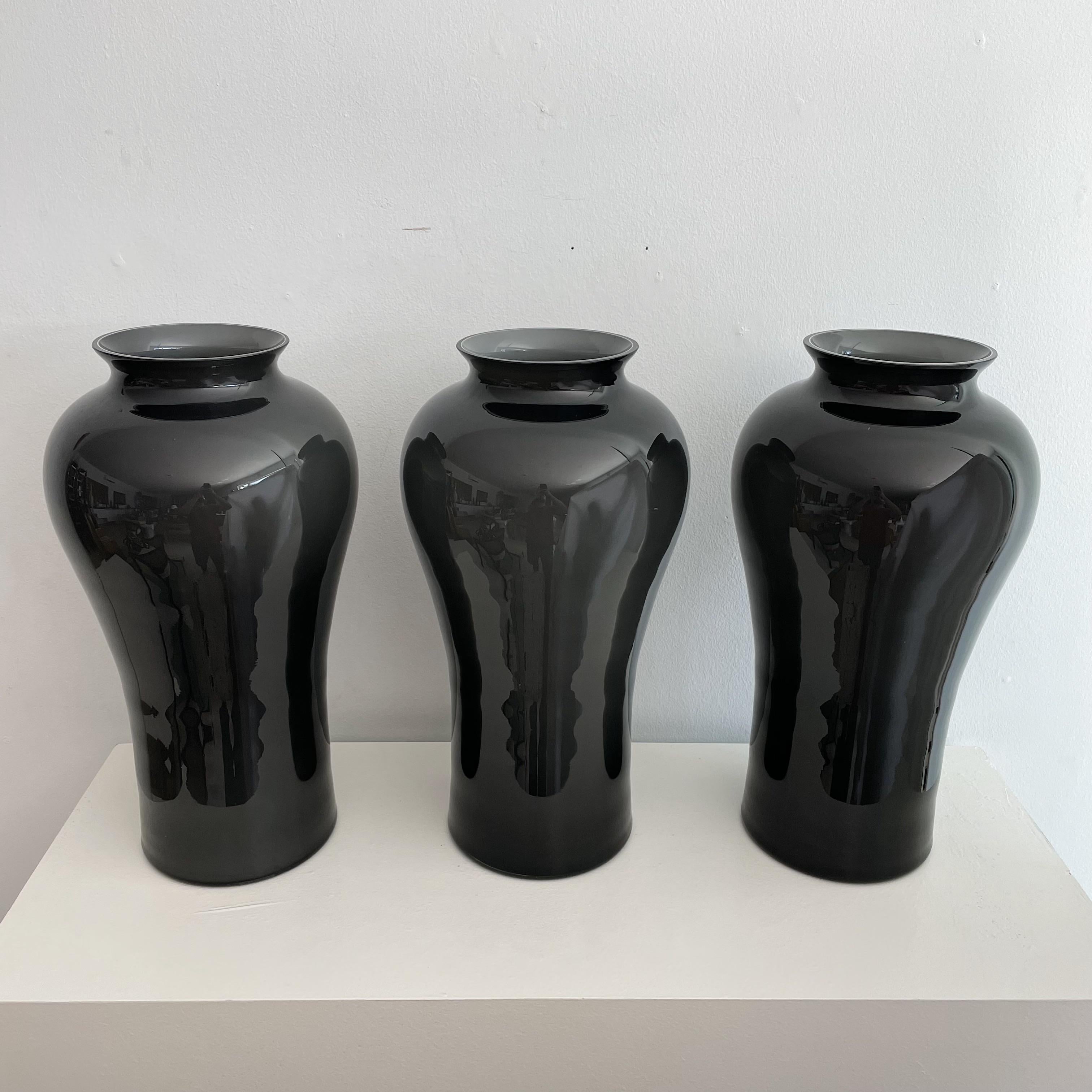 Cased Murano glass vases. Each signed Cenedese on underside with blue and silver Murano label. In a graduating smokey gray color with a lighter grey on interior and white casing. Circa 1984. Neck width is 4.75. Priced per item.