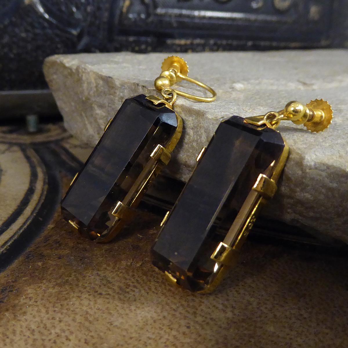 These lovely vintage earrings have been crafted from 9ct Yellow Gold with clear stamps on the settings. The earrings feature a single Smokey Quartz stone in a six flat claw setting. The earrings are screw back and do not have need for the ears to be