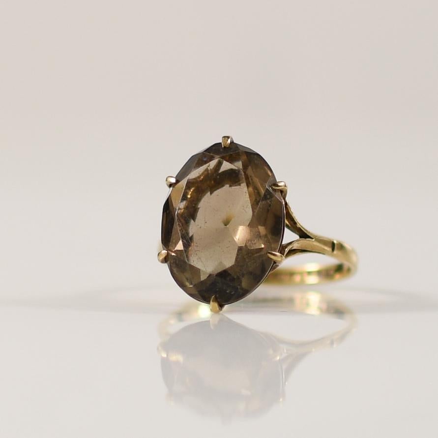 Dieser Vintage-Ring von Charles Lyster & Sons, der 1976 in Birmingham, Großbritannien, gefertigt wurde, besticht durch einen Rauchtopas, der von eleganten Zacken gehalten wird. Die warmen Farbtöne des Topas werden durch die fachmännische