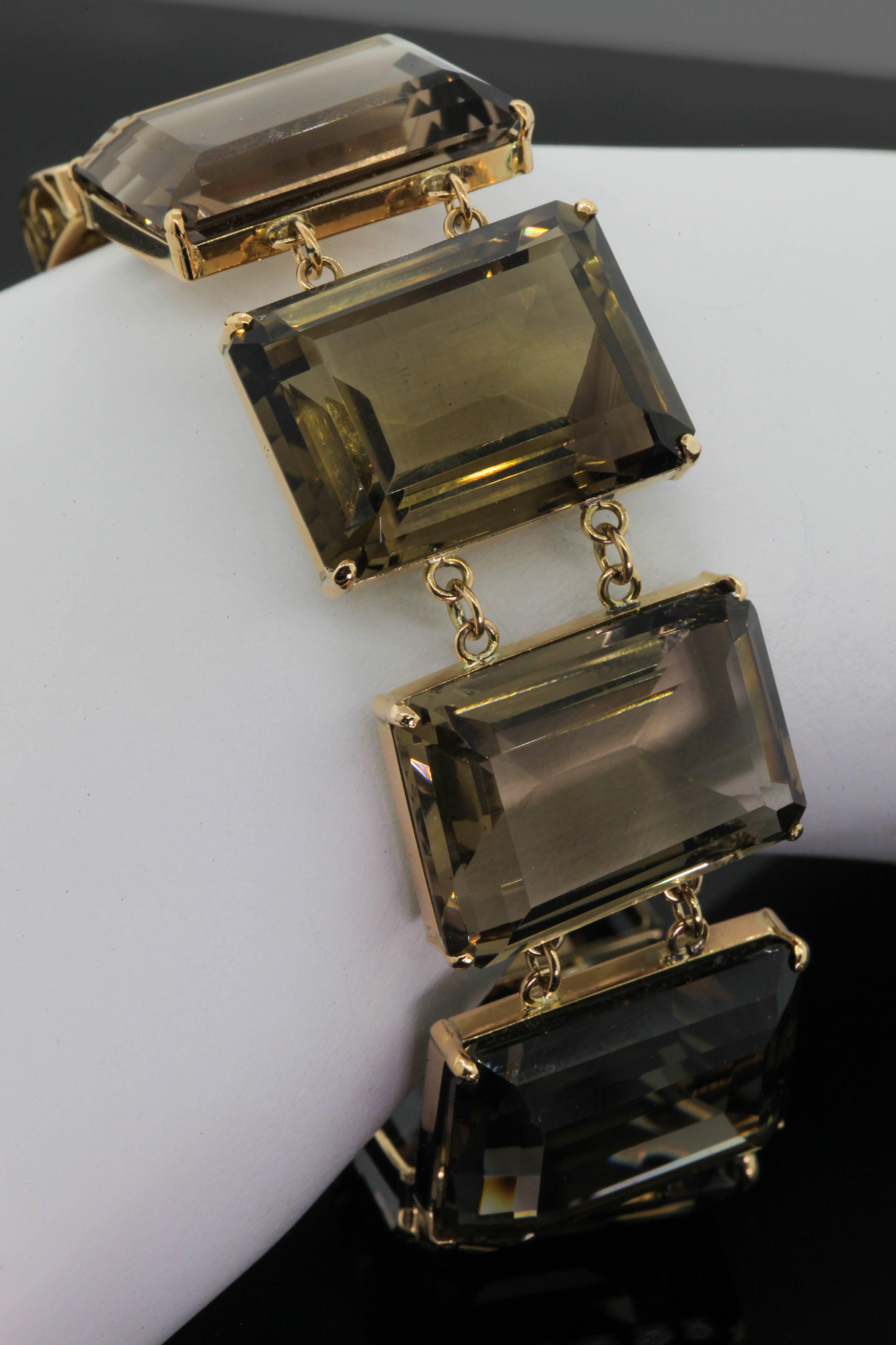 A coveted 1950s 18KT yellow gold bracelet stunningly set with eight emerald cut Smoky Citrine all weighing a total of approx. 168 carat.   The bracelet is enhanced with gold links joining each Citrine and is set with a wide tongue and clasp.  