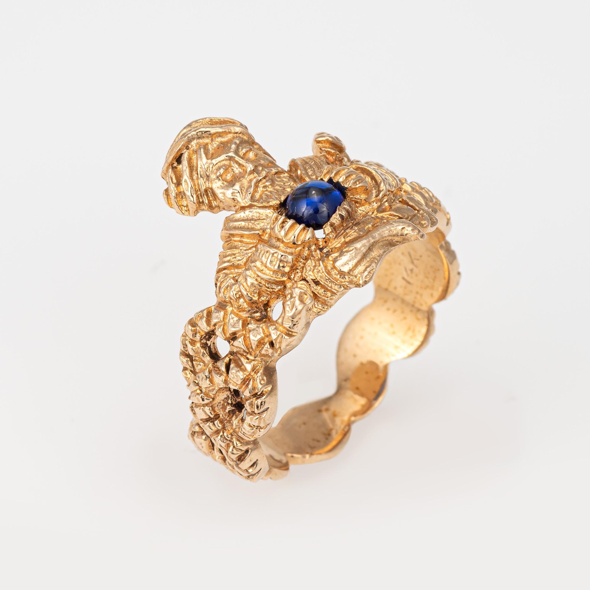 Finely detailed snake charmer ring (circa 1960s to 1970s) crafted in 14 karat yellow gold. 

Cabochon cut sapphire measures 4mm. The sapphire is in good condition and free of cracks or chips. 

The glowing cabochon cut sapphire 