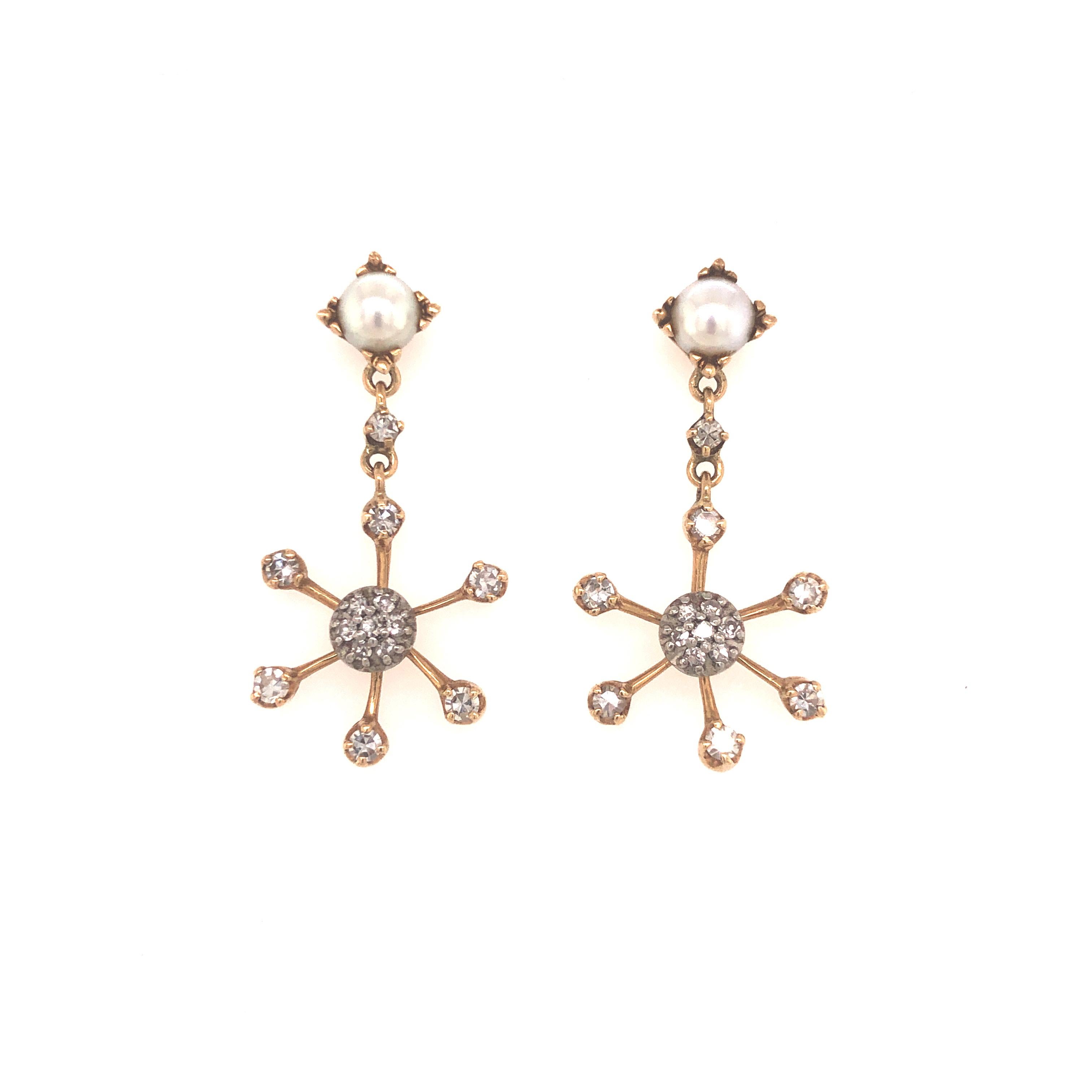 Beautifully crafted vintage earrings crafted in 14k yellow gold. The earrings depict a snowflake design or also known as starburst. The earrings are set with a pearl stud secured with a screw back post. Dangling from the pearl is the snowflake