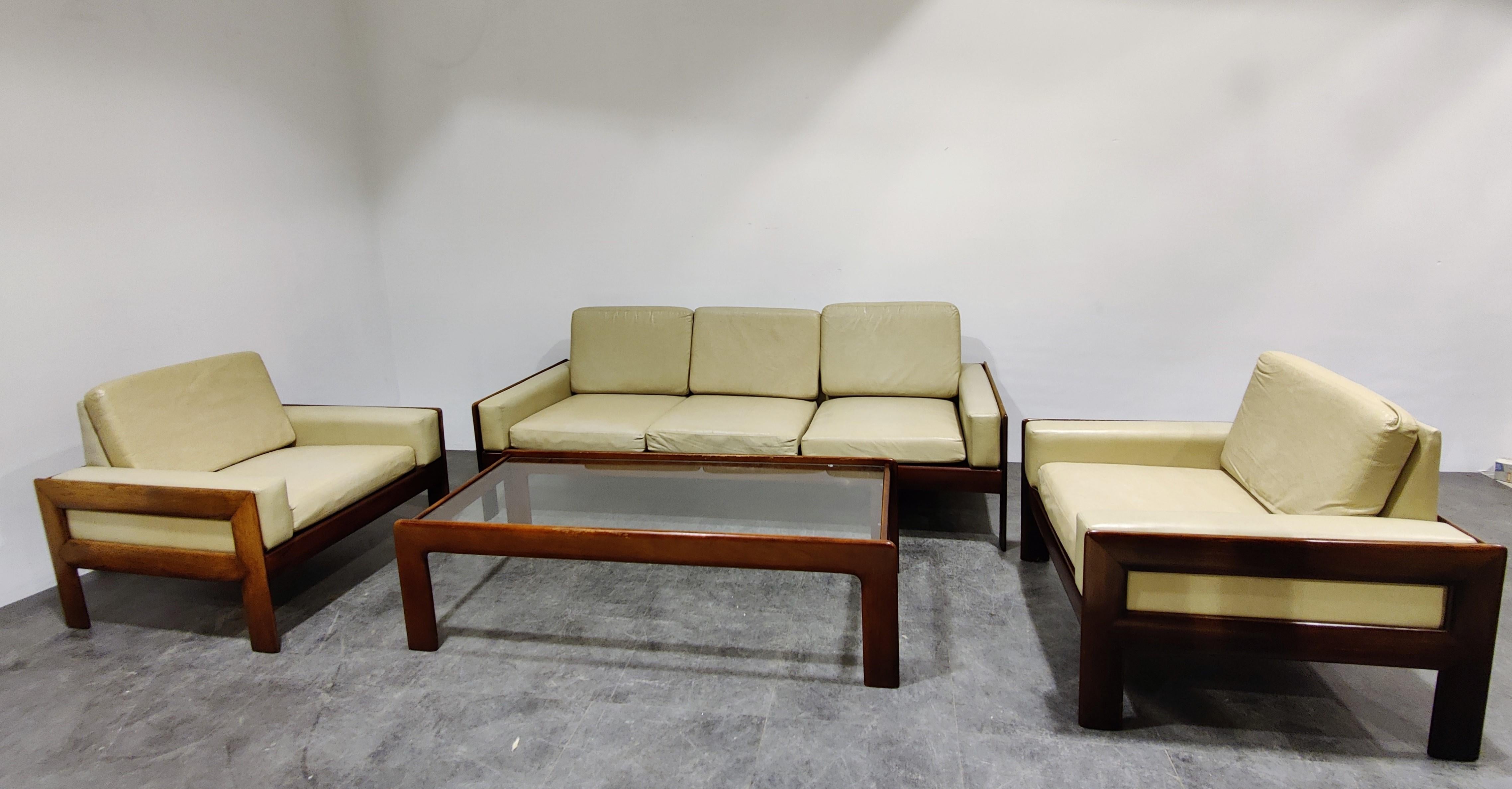 Midcentury living room set consisting of two armchairs, one three seater sofa and a coffee table.

Beautiful elegant and sleek design very much in the style of Tobia Scarpa's Bastiano sofa.

They come with the original off white faux leather