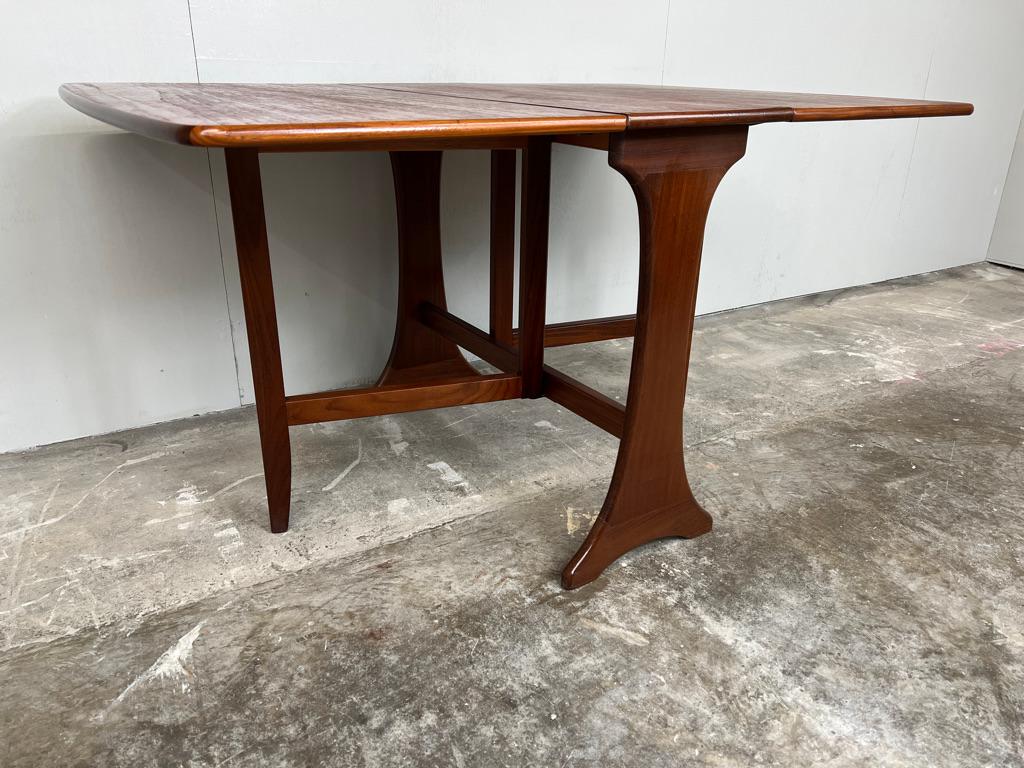 Il s'agit d'une table de salle à manger en teck danois de qualité, avec de superbes pieds en forme, et les deux feuilles sont un excellent gain de place, idéal pour un petit appartement ou un condominium.

Cette élégante table à abattant en teck
