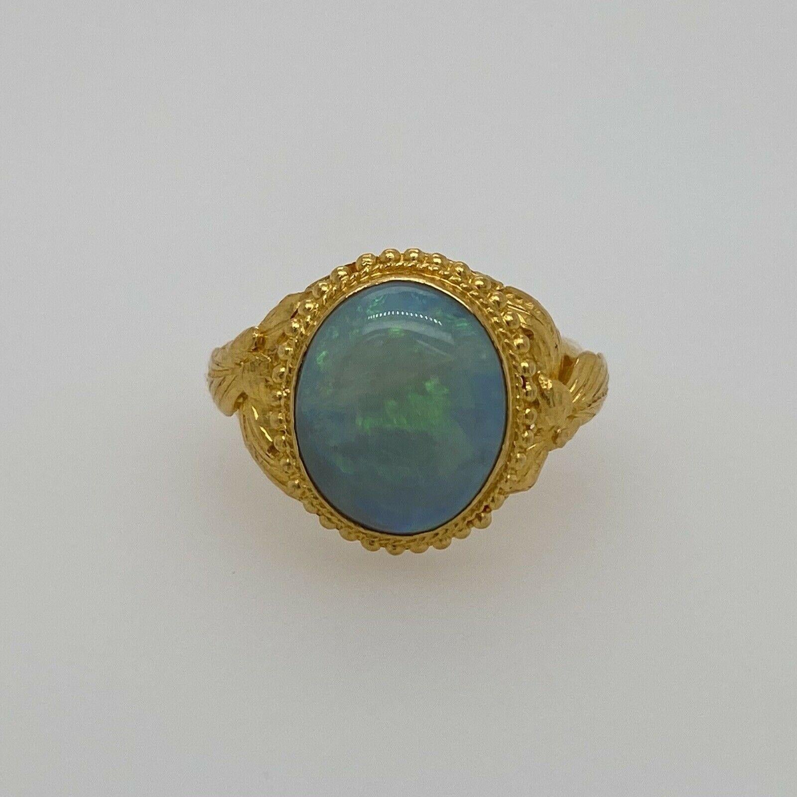 Excellent condition. This vintage ring is composed of solid 24K gold with ornate details and holds a vibrant opal. This opal measures approximately 12mm X 9.85mm. This opal is blue and green with flashes of red, orange & yellow. It is a size 5.5 and