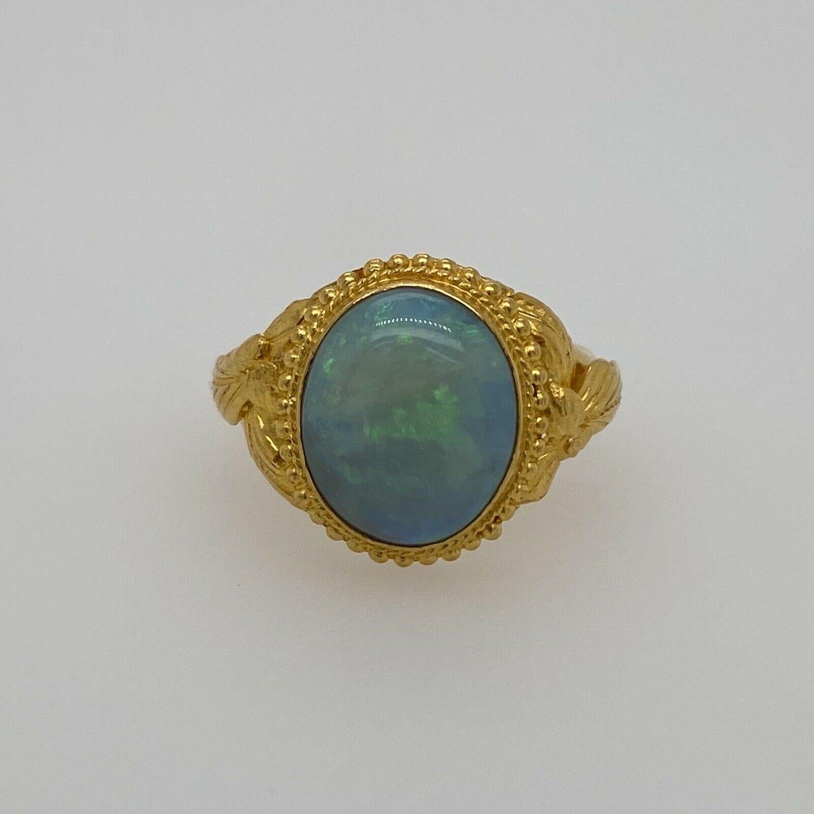 Excellent condition. This vintage ring is composed of solid 24K gold with ornate details and holds a vibrant opal. This opal measures approximately 12mm X 9.85mm. This opal is blue and green with flashes of red, orange & yellow. It is a size 5.5 and