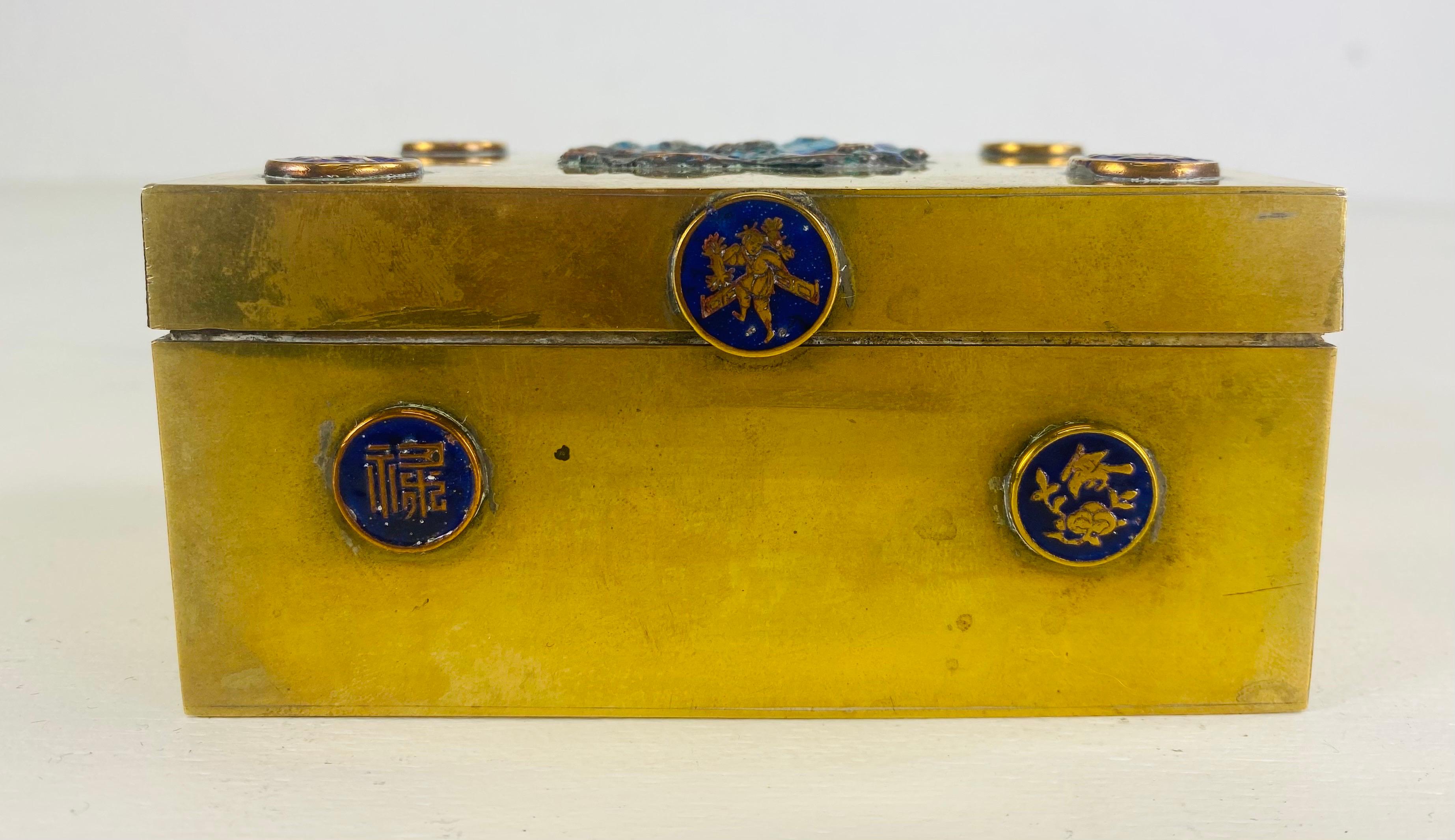 This is a vintage Chinese export solid brass and enamel trinket box. This solid brass box has four medallions on the top and medallions on each side of the box. The top of the box features one large center medallion that has blue enamel. The box was