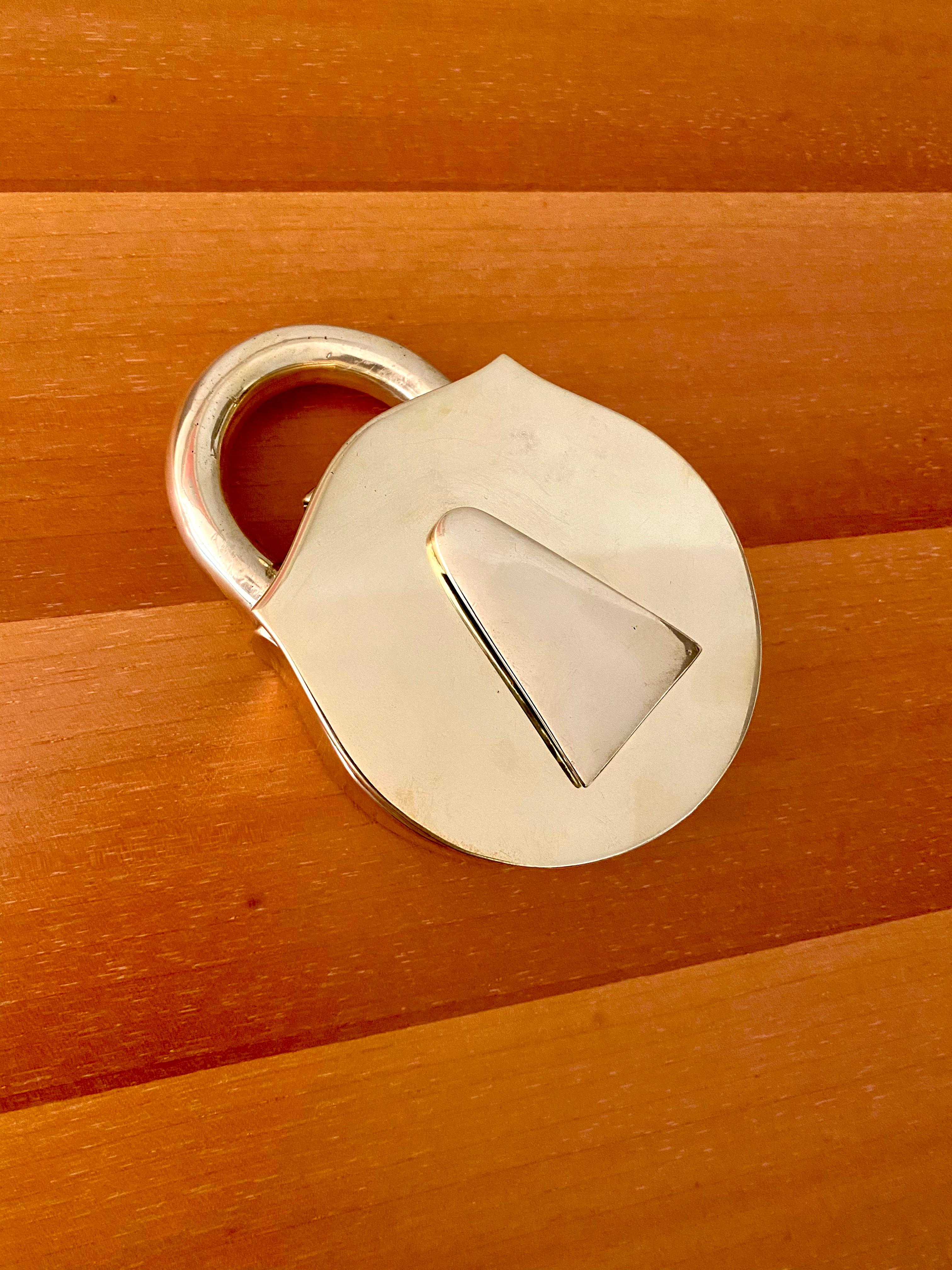 A heavy solid brass padlock, which opens to a black interior, and has a movable key cover, manufactured in Waynesboro, Virginia by Virginia Metalcrafters. The padlock was originally intended to be an ashtray, but can be used as a paper weight or box