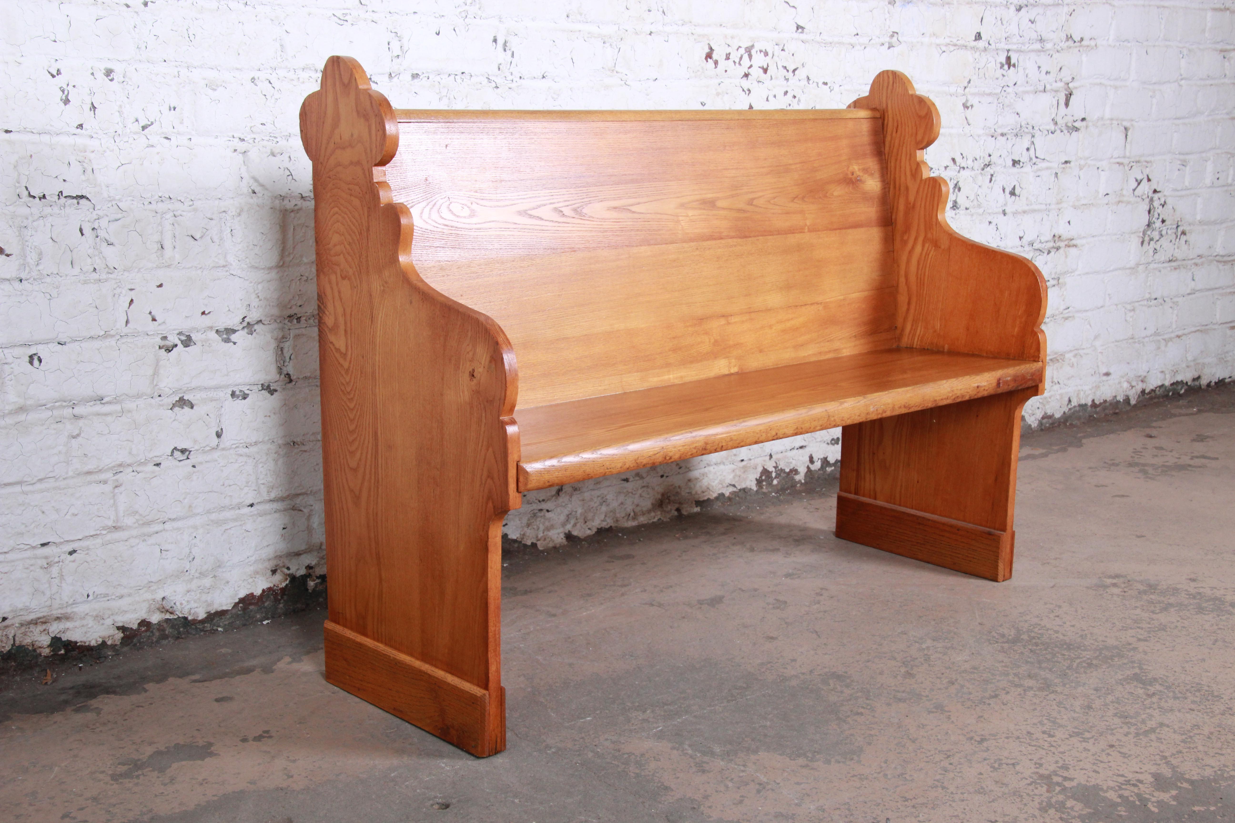 A gorgeous quartersawn oak Gothic Cathedral church pew or bench. It features beautiful wood grain and nice carved wood details. Would make an excellent entry bench. There is a unique Celtic medallion on the top of the seat back. The bench is solid