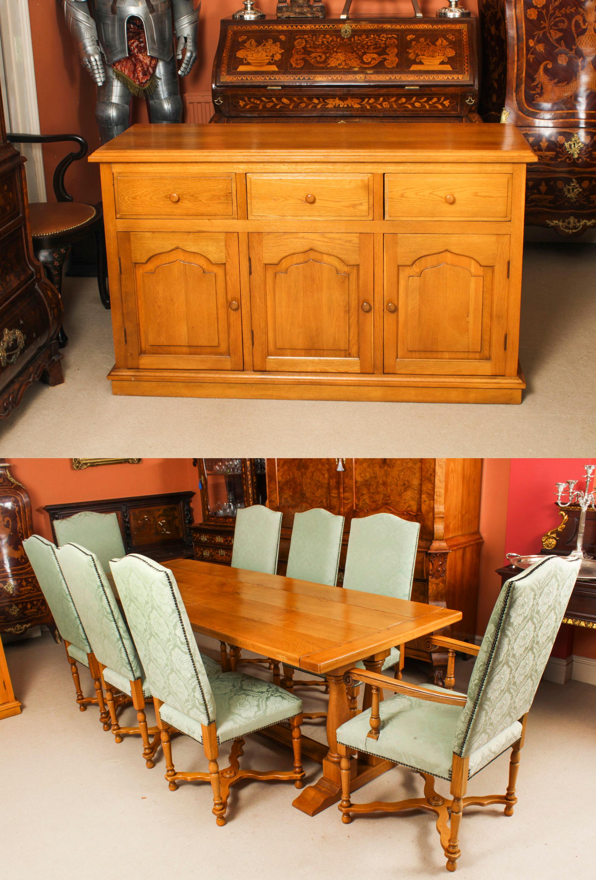 An exquisite English solid oak dining suite comprising a refectory table, a set of eight upholstered back chairs and a sideboard, made by Brights of Nettlebed and dating from the late 20th Century.

This beautiful refectory table, the chairs and the