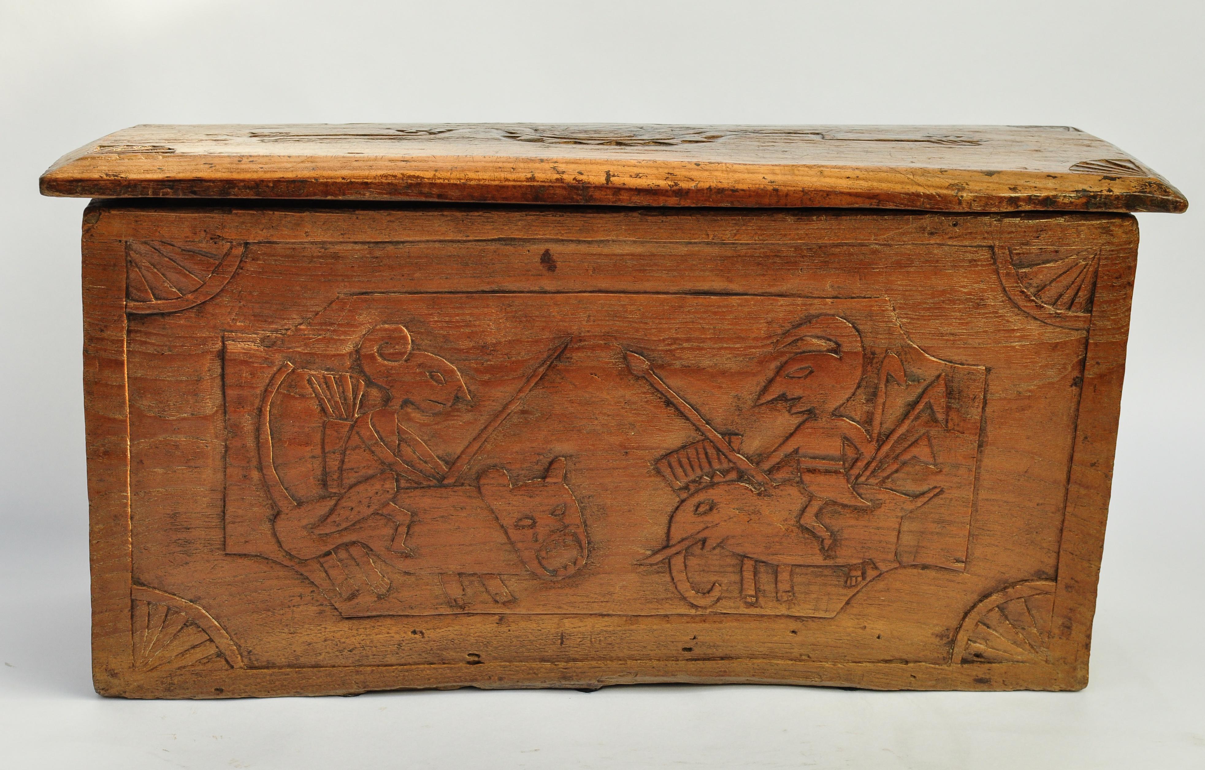 Vintage solid teak storage box with carvings. Java, Early to Mid-20th Century. 
This absolutely charming box, in a rural folk art style, is hewn out of a single piece of teak. On the one side two warriors face off, one mounted on a tiger, the other