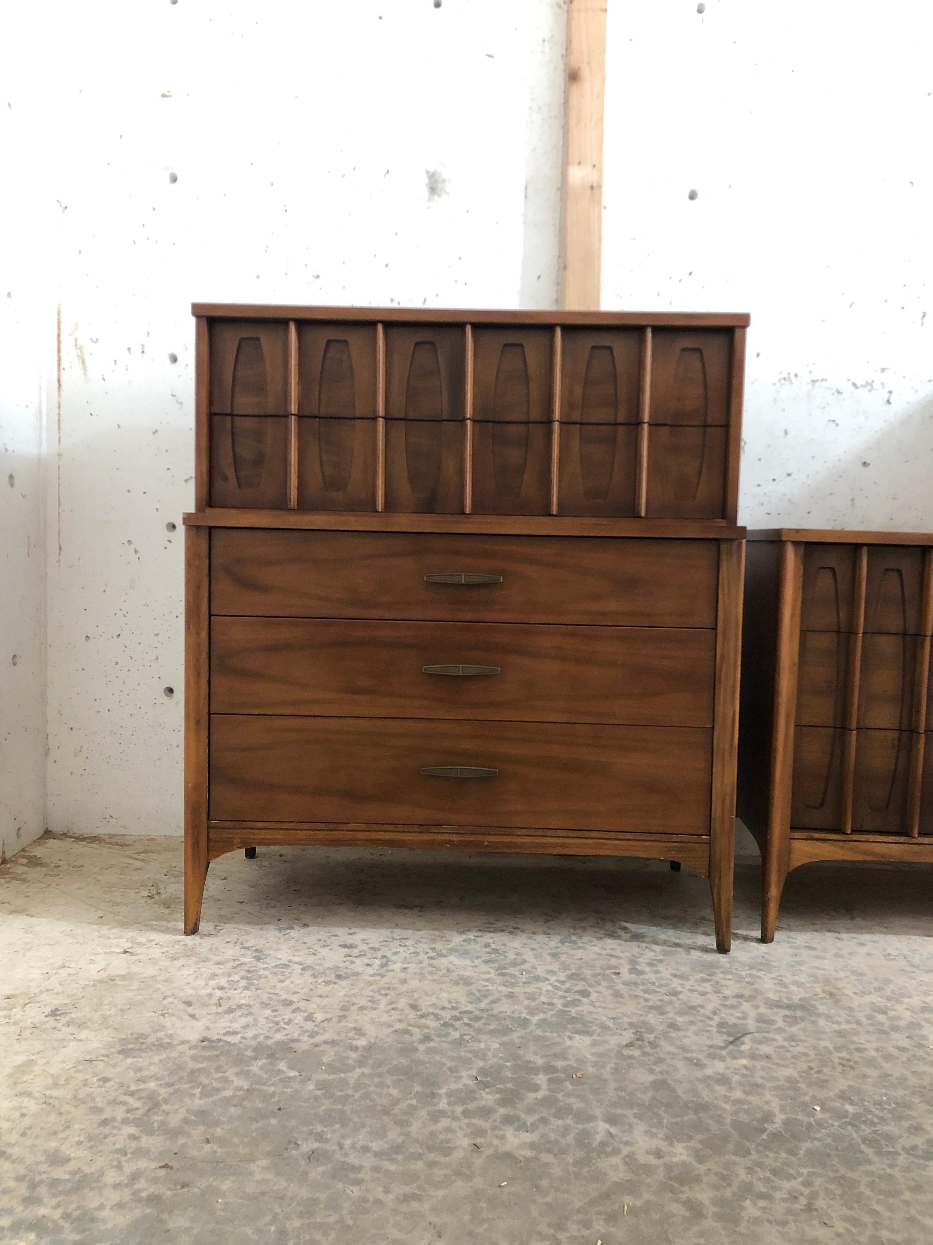This stylish Kent Coffey dresser has lovely recessed scalloped accents and vertical wood pulls! Sleek and sculpted design with textured brass pull on bottom three drawers and solid walnut wood.

Dimensions: 40 W 18 D 46 H.