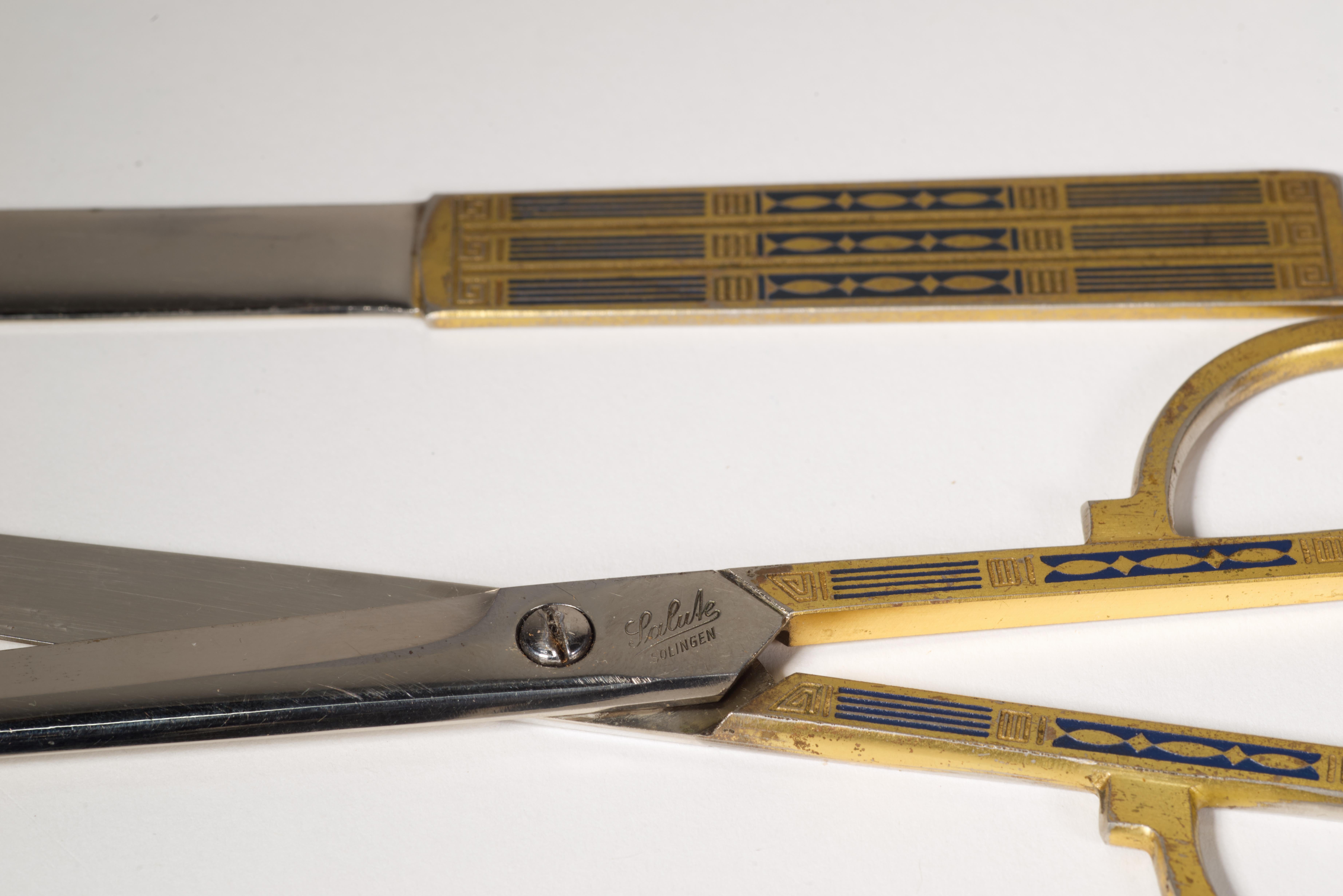 
Vintage set of scissors and letter opener features brass plated handles with engraved Arts and Crafts style decor, done in black matte enamel. The pieces are stored in navy leather case, with decorated side displayed and stainless-steel blades