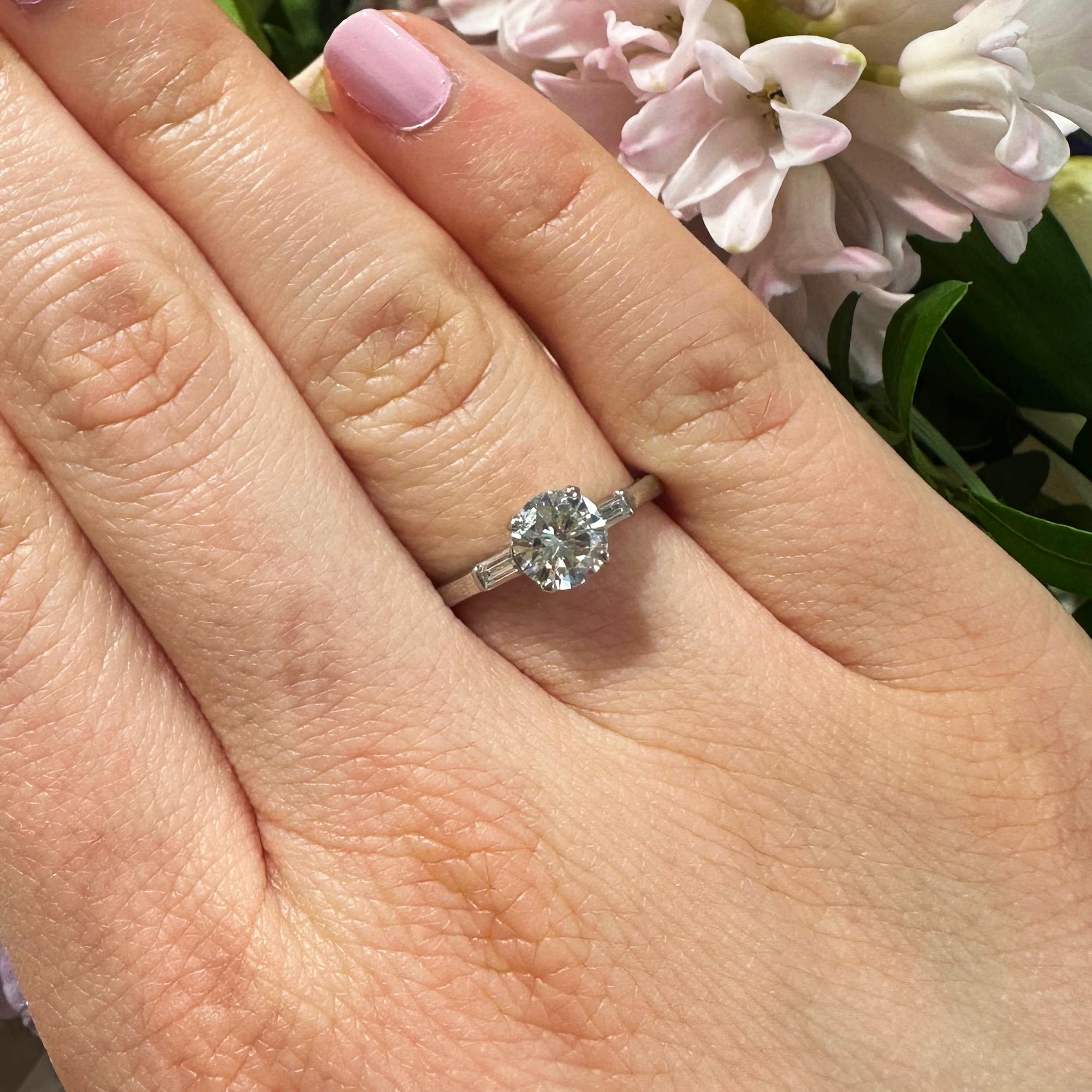 A vintage single stone diamond ring, set with a 0.81 carat, E-F colour, VS1 clarity, round brilliant-cut diamond, in a four claw setting, with baguette-cut diamond set shoulders, mounted in platinum, with a maker's mark for J. & L. Hartzberg,