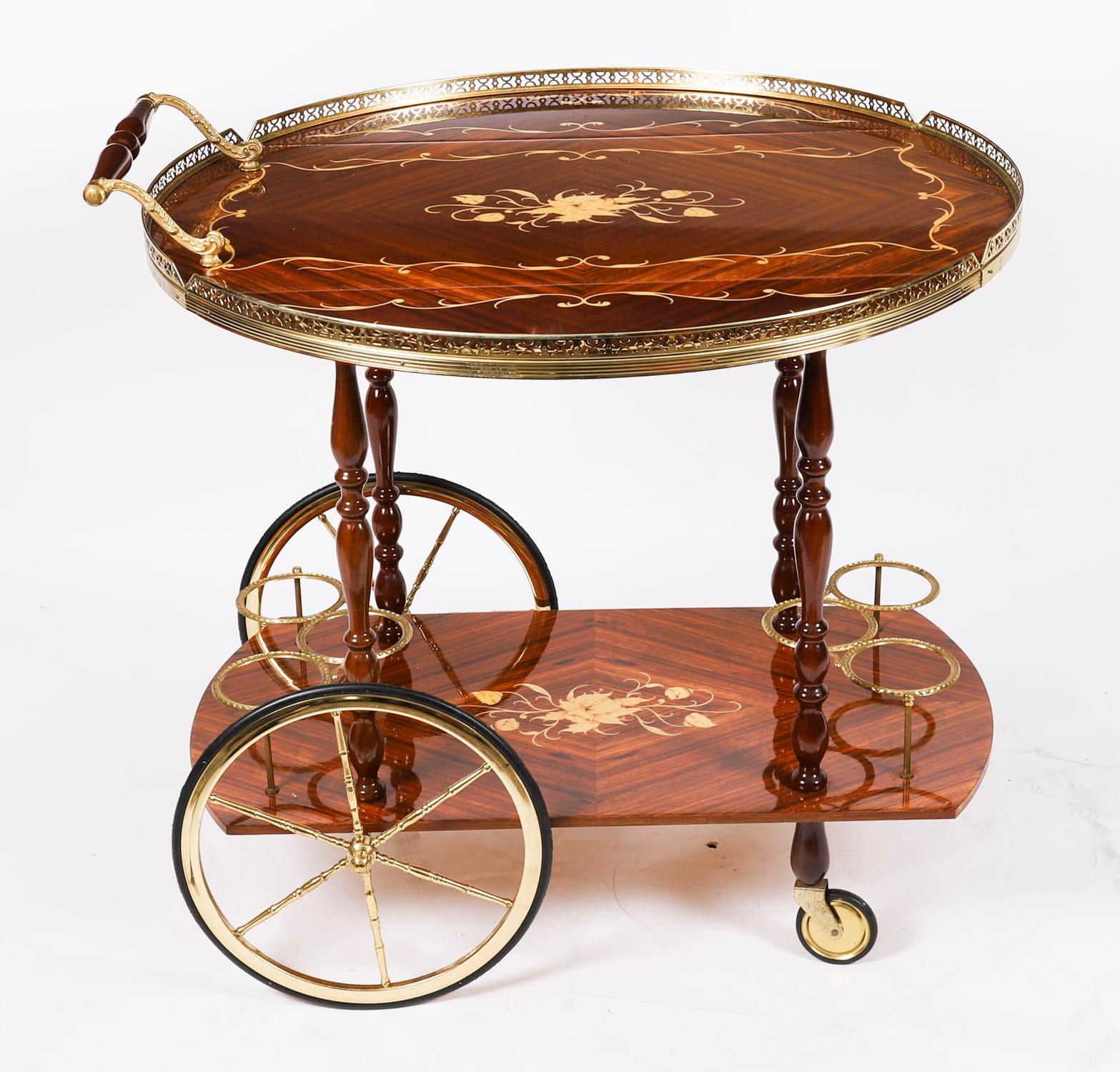 Si tratta di un divertentissimo carrello portabevande italiano a due piani di Sorrento, risalente alla metà del secolo scorso.

Il piano ovale con alette presenta una decorazione floreale a intarsio con un mazzo di fiori centrale e una fascia a