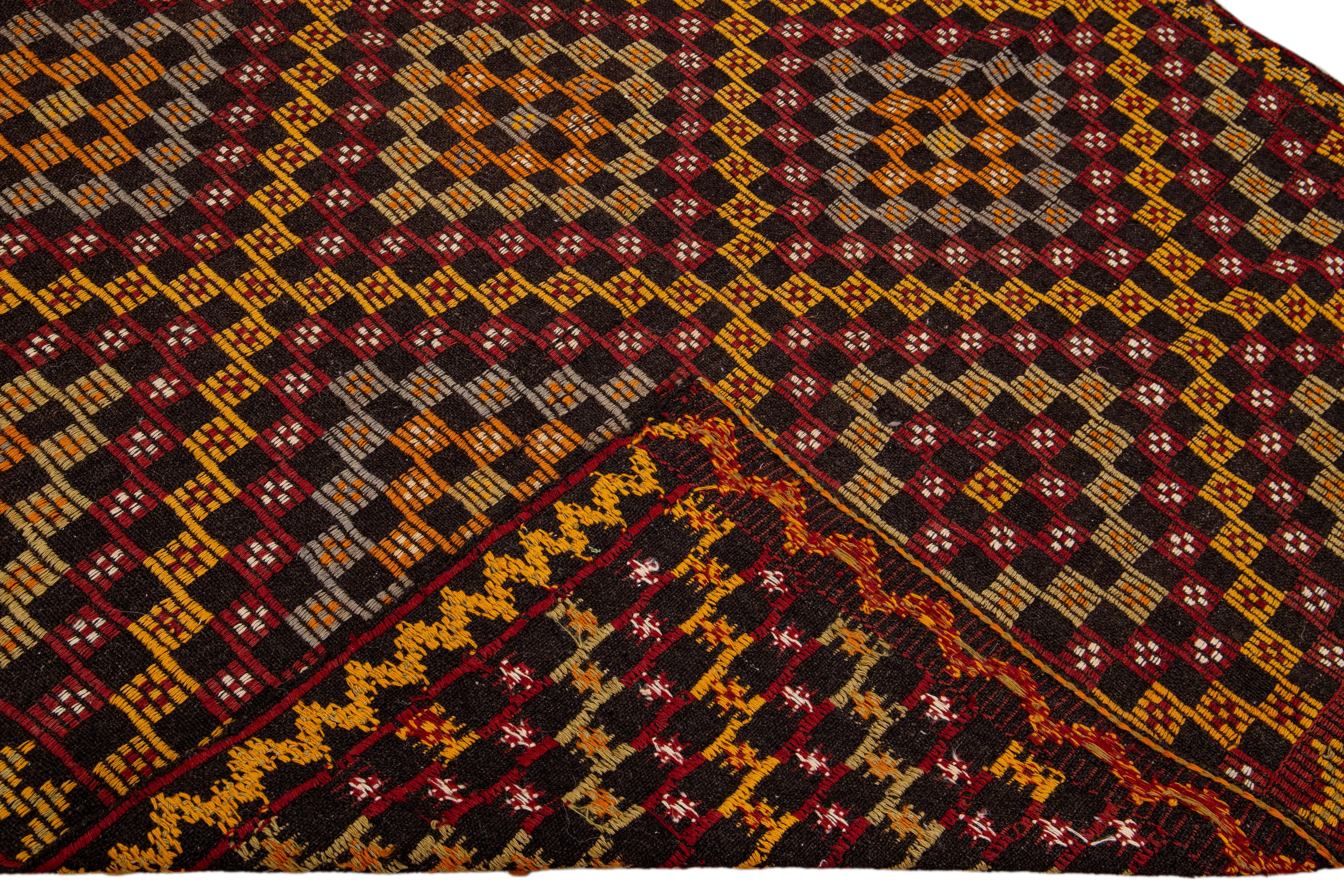 Beautiful vintage Soumak hand-knotted wool rug with a brown field. This piece has yellow, red, orange, and gray accents in a gorgeous all-over geometric medallion motif design.

This rug measures 5'6