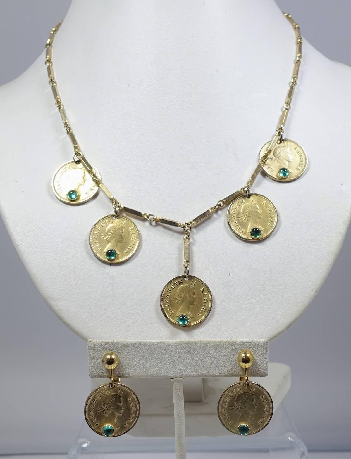 This vintage set features South African faux coins with green cabochon glass accents in a gold tone metal setting.  The necklace measures 18-1/2” long with a spring closure and each coin is 3/4” wide. The matching clip earrings hangs 3/4